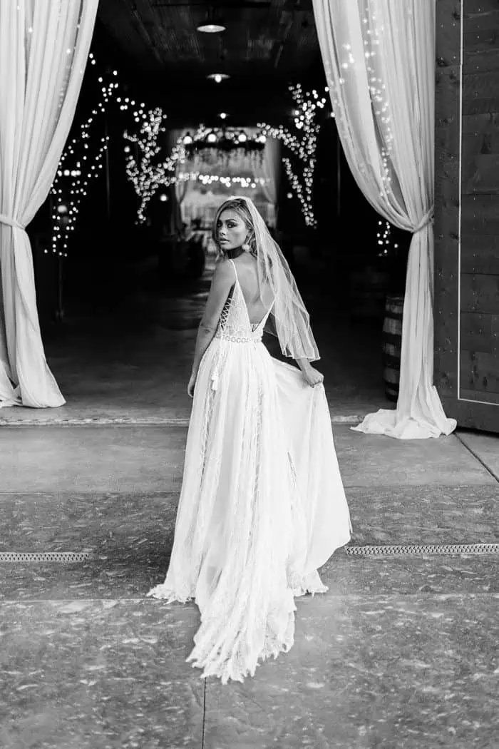 Bride in a flowing wedding gown standing in a decorated reception hall.