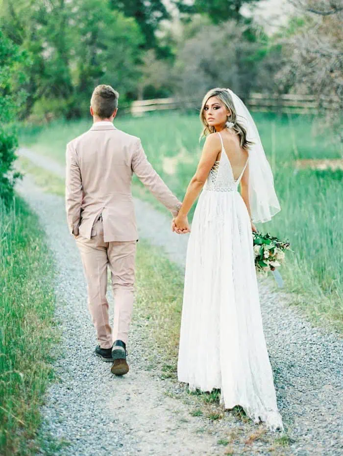 Elegant bride and groom holding hands outdoors in a scenic natural setting.