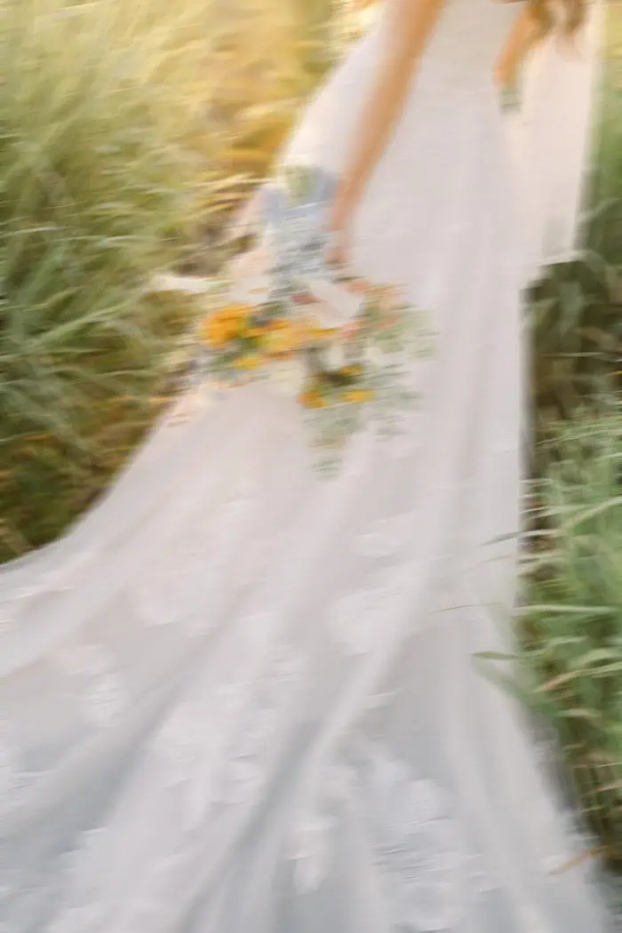 Wedding dress with floral bouquet in a lush garden setting.