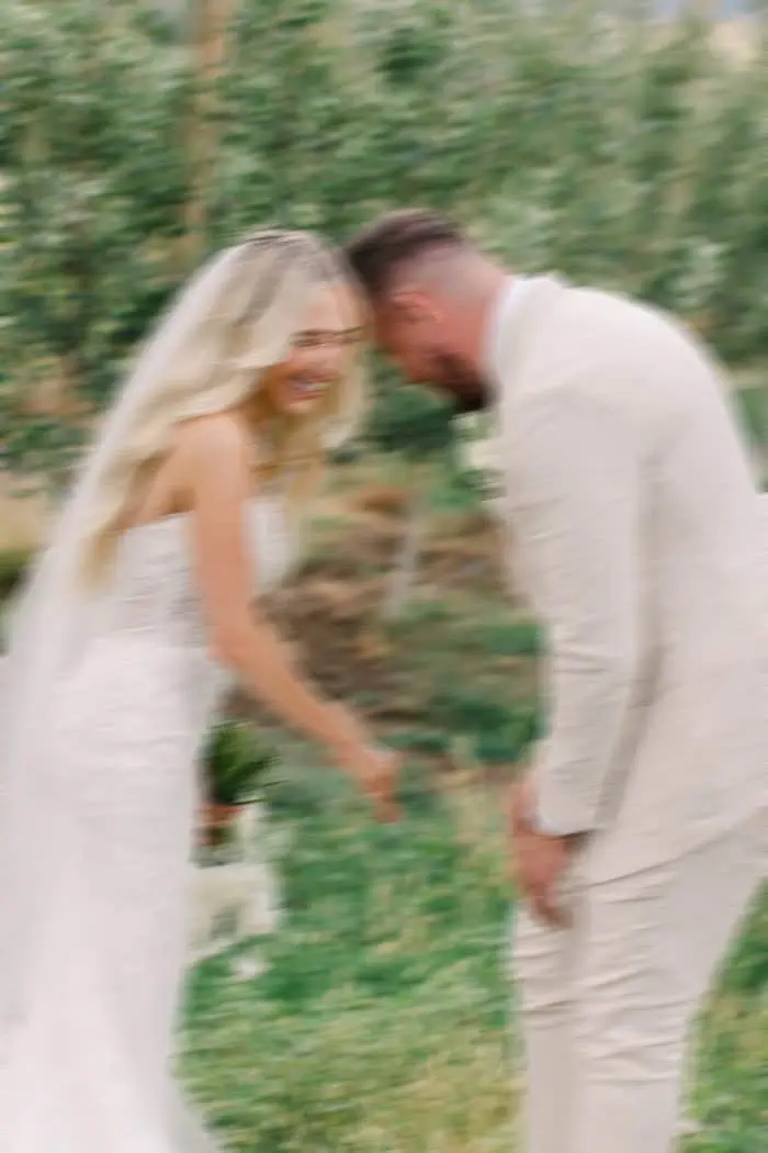 Wedding couple in a natural outdoor setting, smiling and holding hands.