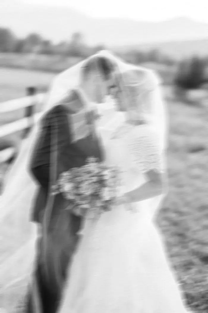 Wedding couple sharing a kiss outdoors with a blurred background.