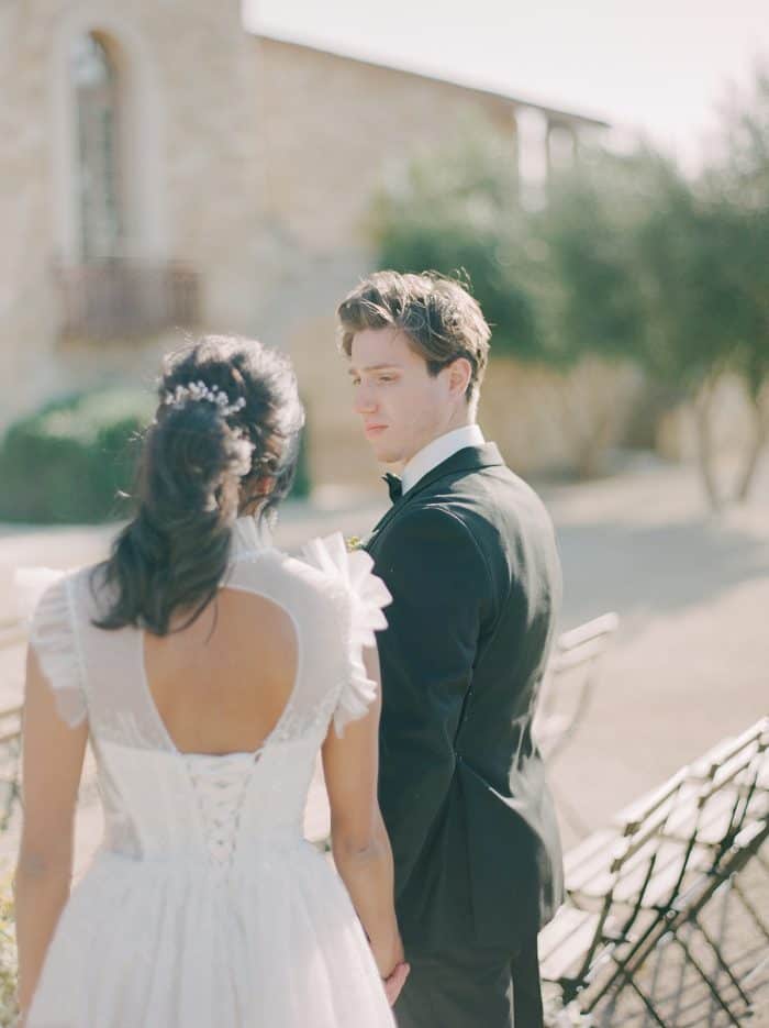 Wedding couple in formal attire outdoors, romantic moment captured in natural sunlight.