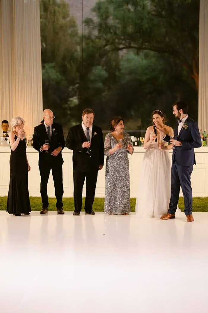 Wedding guests raising glasses during a joyful celebration at a scenic indoor venue.