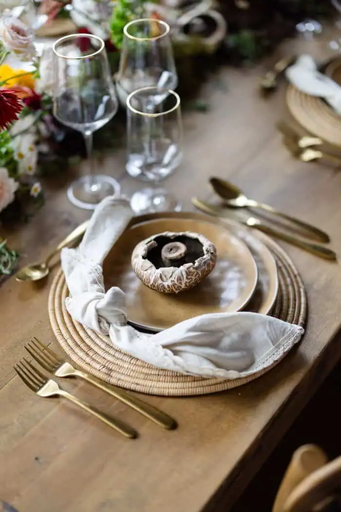 Elegant table setting with gold cutlery, glassware, and a mushroom centerpiece for a sophisticated e.