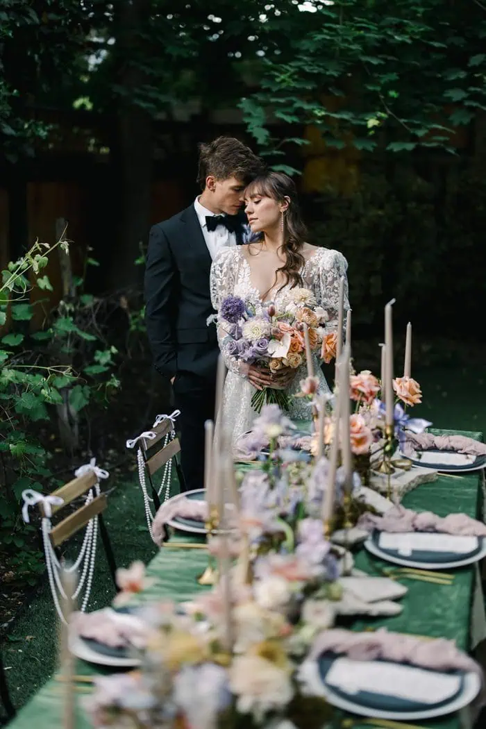 Romantic wedding scene featuring a bride and groom with a beautifully decorated table outdoors.