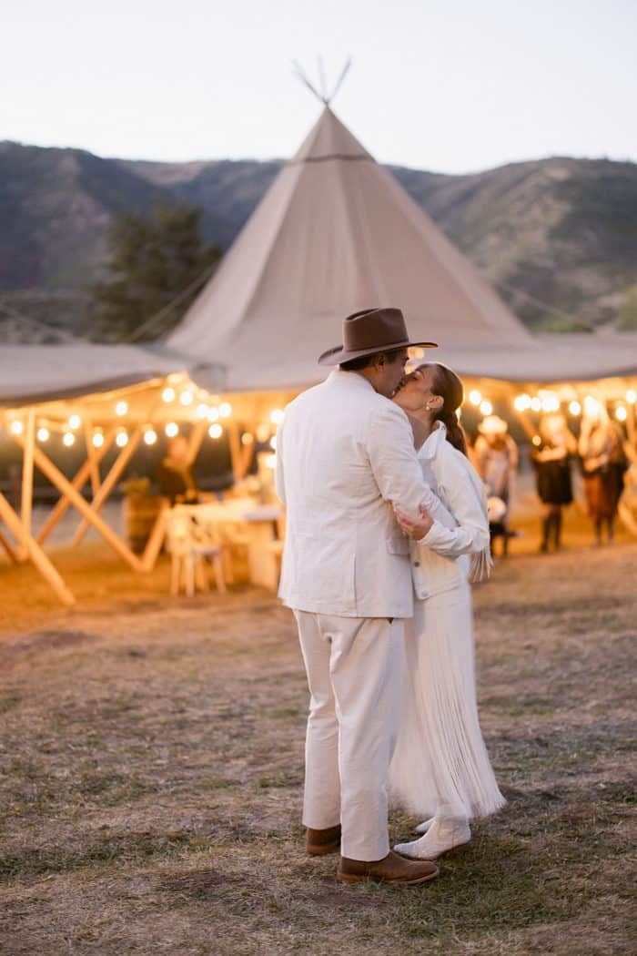 Elegant bohemian wedding couple embracing outdoors.