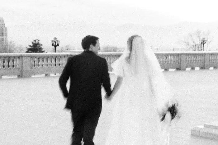 Wedding couple walking hand in hand on a bridge during sunset.