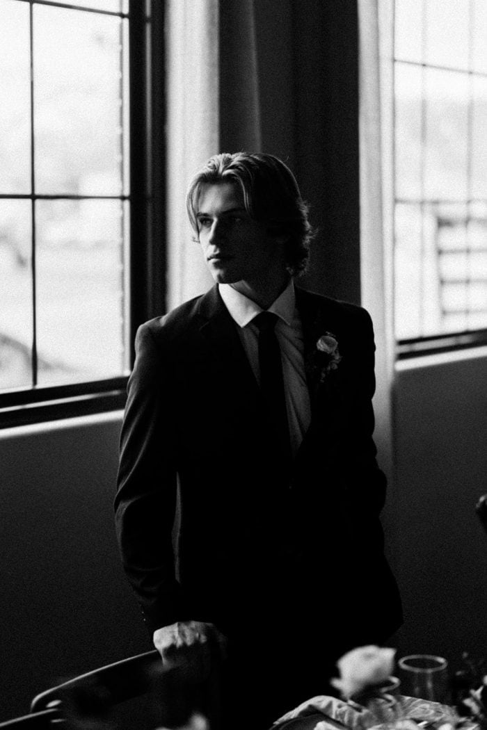 Black and white portrait of a man in a suit by a window, professional photography.