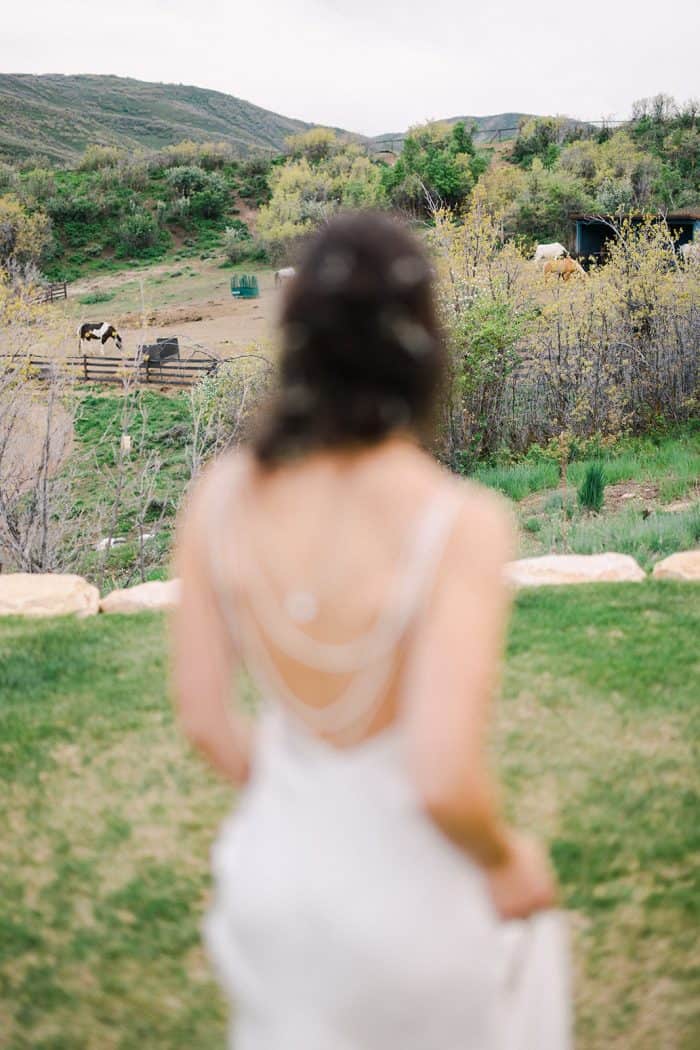 Woman in a white dress standing outdoors with a scenic rural landscape in the background.