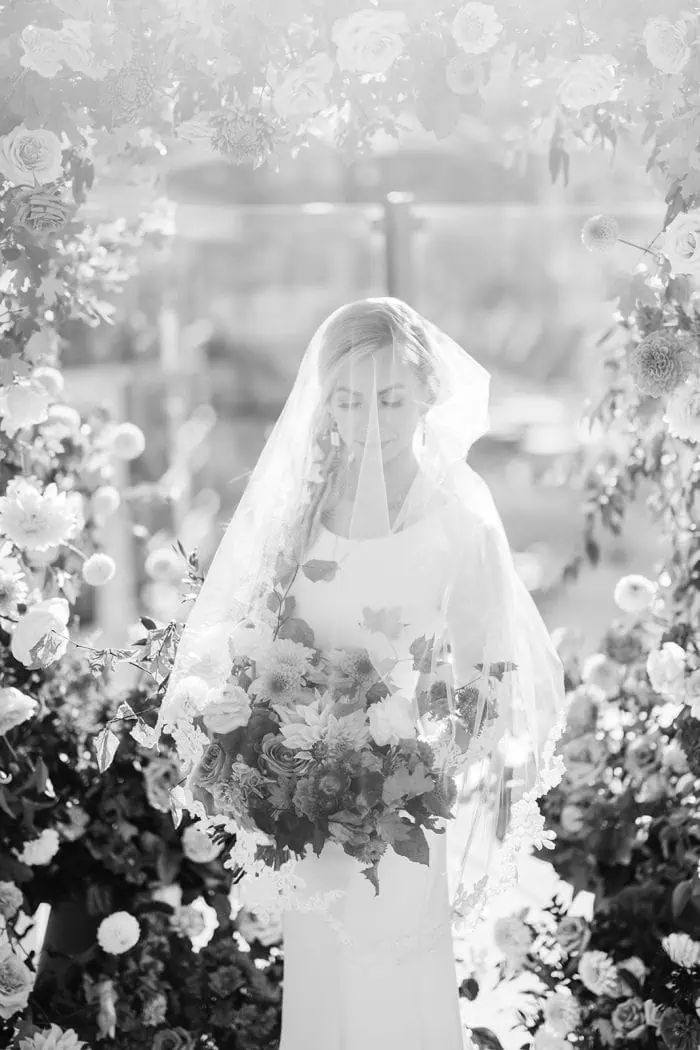 Bridal portrait of a bride with a floral bouquet, surrounded by flowers, in a professional photograp.