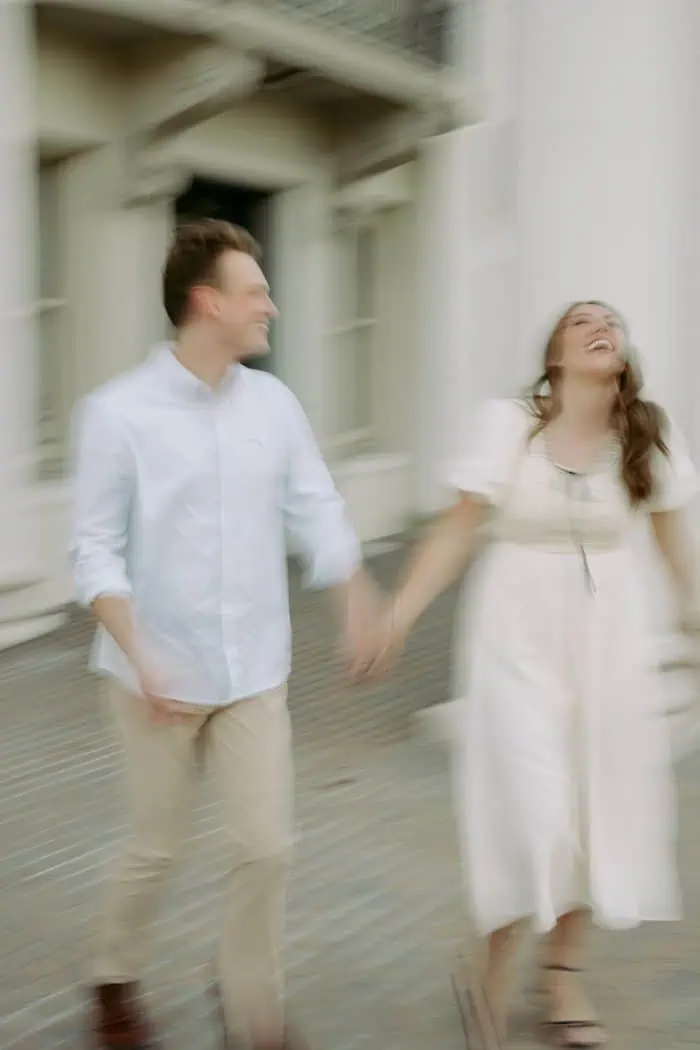 Happy couple holding hands and walking together in an urban setting.