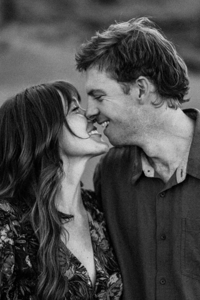 Close-up of a smiling couple touching noses in a black-and-white photo.