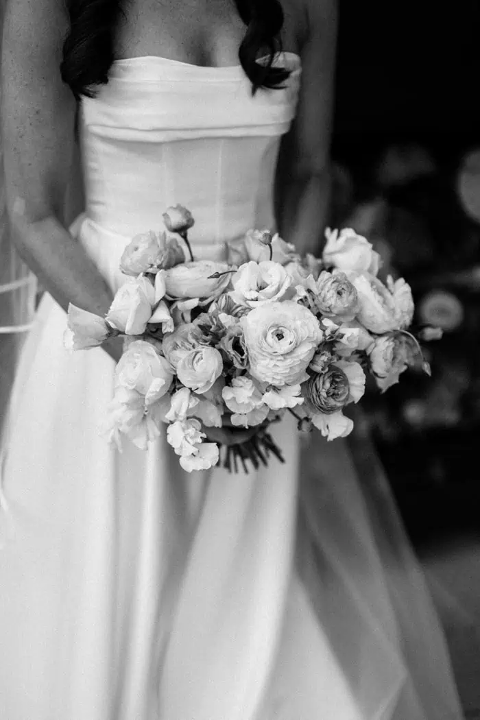 Elegant bride holding a bouquet of roses and ranunculus.