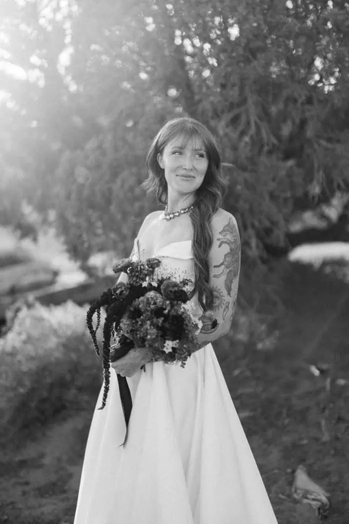 Bride with bouquet outdoors, black and white photography.