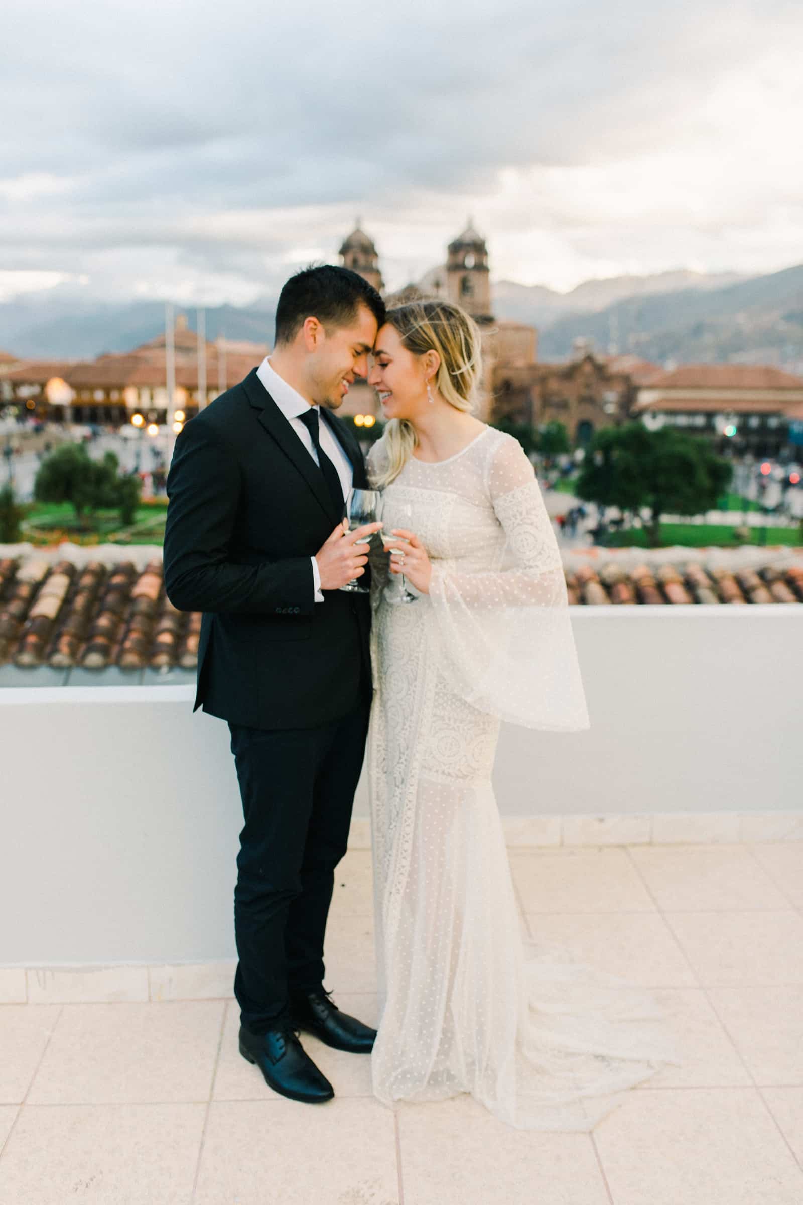 Cusco Peru Destination Wedding Inspiration, travel photography, bride and groom wedding dinner overlooking Cusco Cathedral , champagne toast