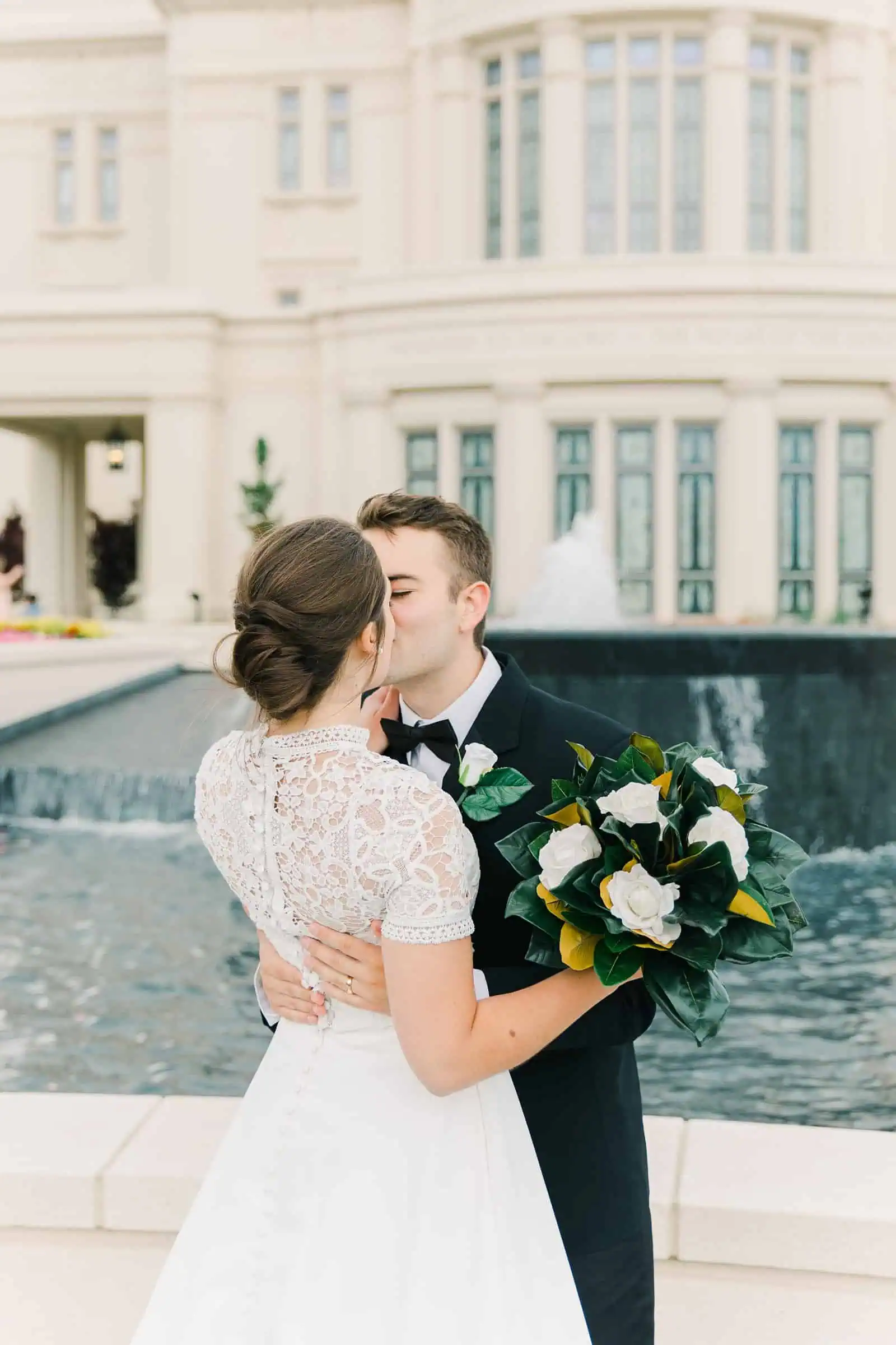 Payson Utah Temple wedding, bride and groom kiss, white rose bouquet with magnolia leaves