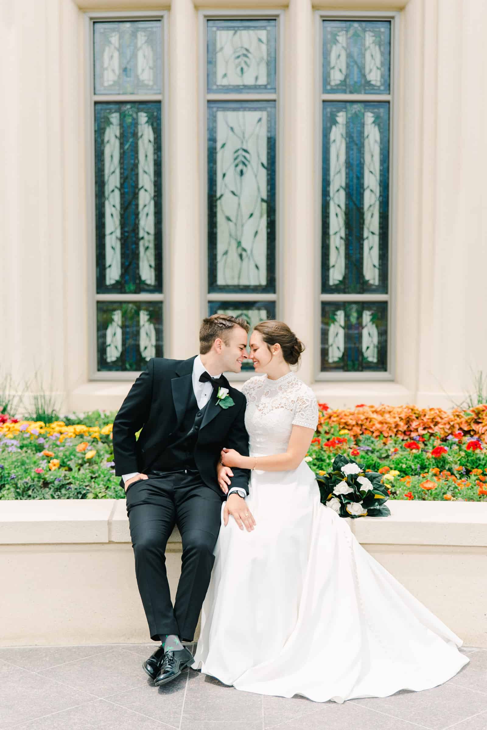 Payson Utah Temple wedding, bride and groom sit near flower garden