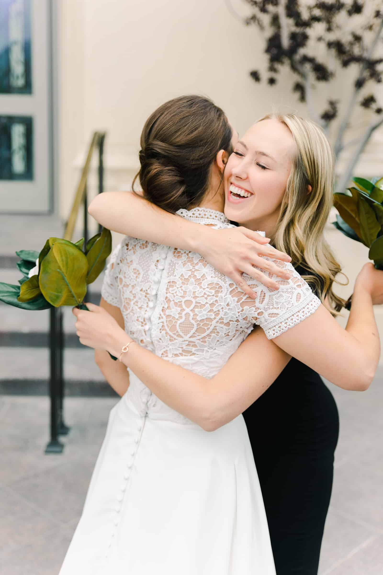 Payson Utah Temple wedding, bride hugs bridesmaid, high collar lace wedding dress