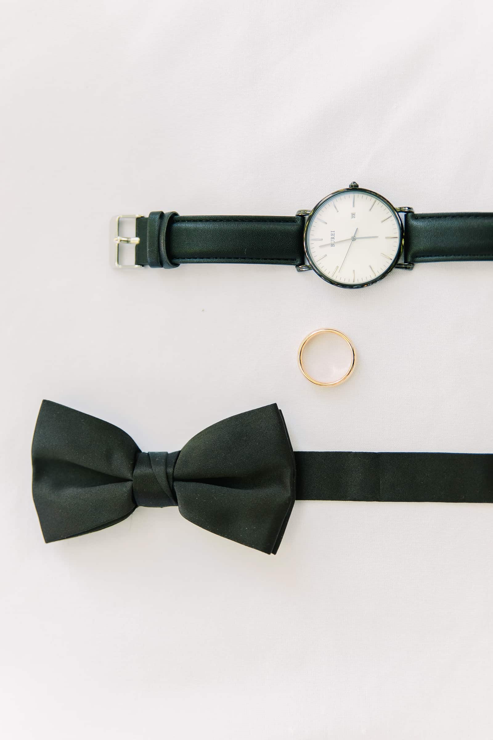 Classic black Utah wedding details, groom black bow tie and watch with gold wedding ring