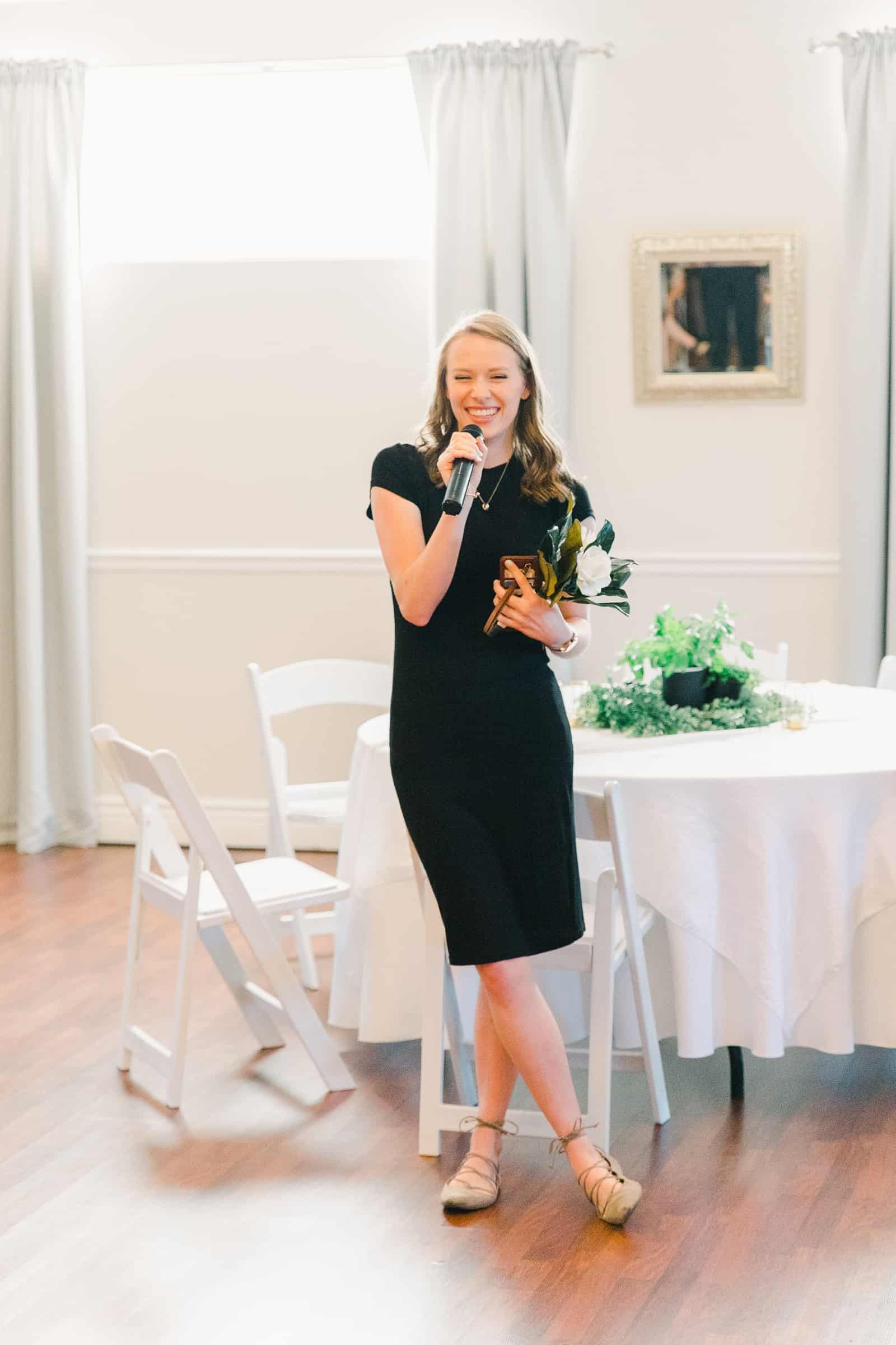 Clarion Gardens Payson Utah Wedding, bridesmaid in black dress gives a toast