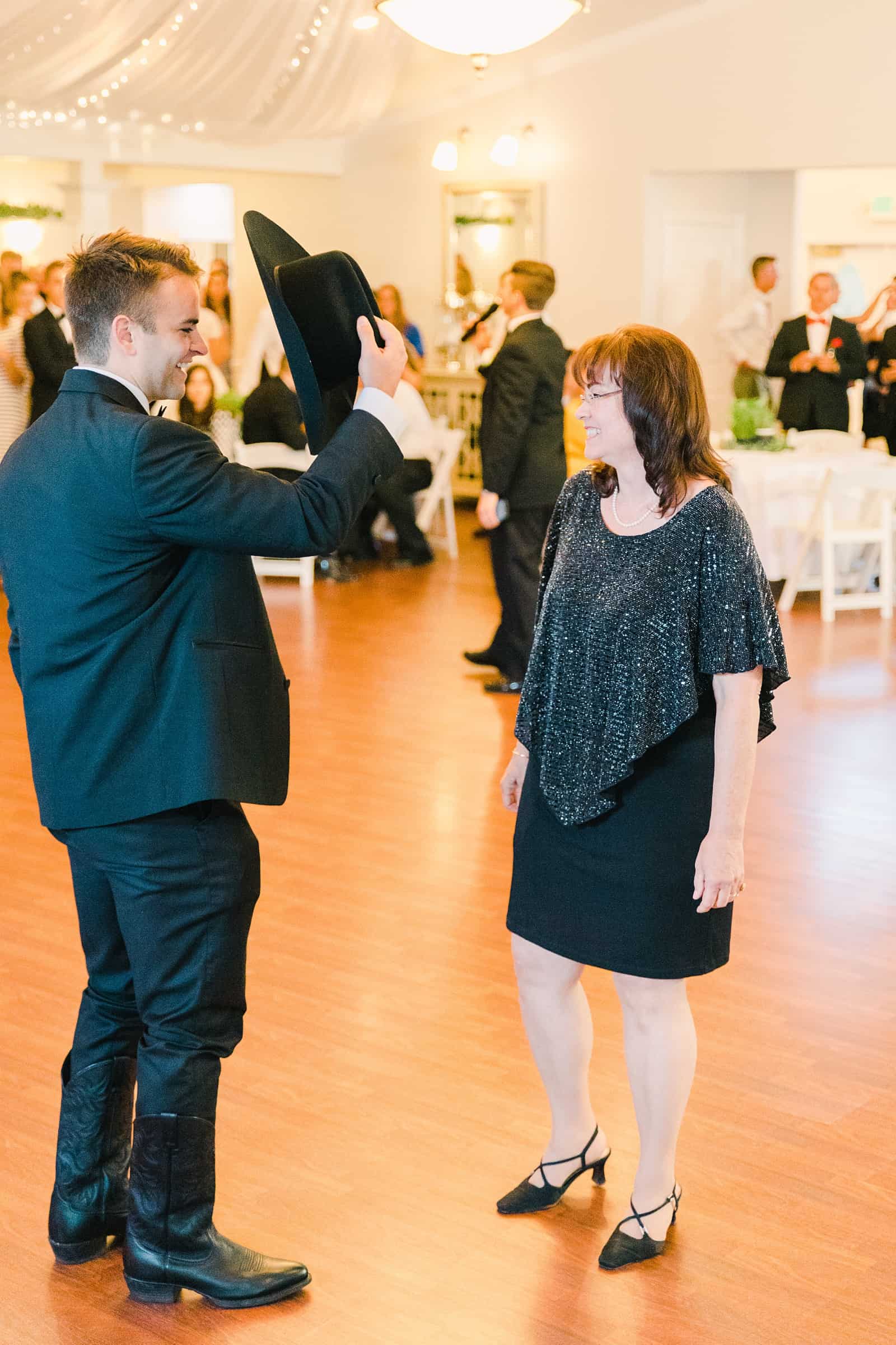 Clarion Gardens Payson Utah Wedding, groom wears cowboy hat and dances with mother of the groom