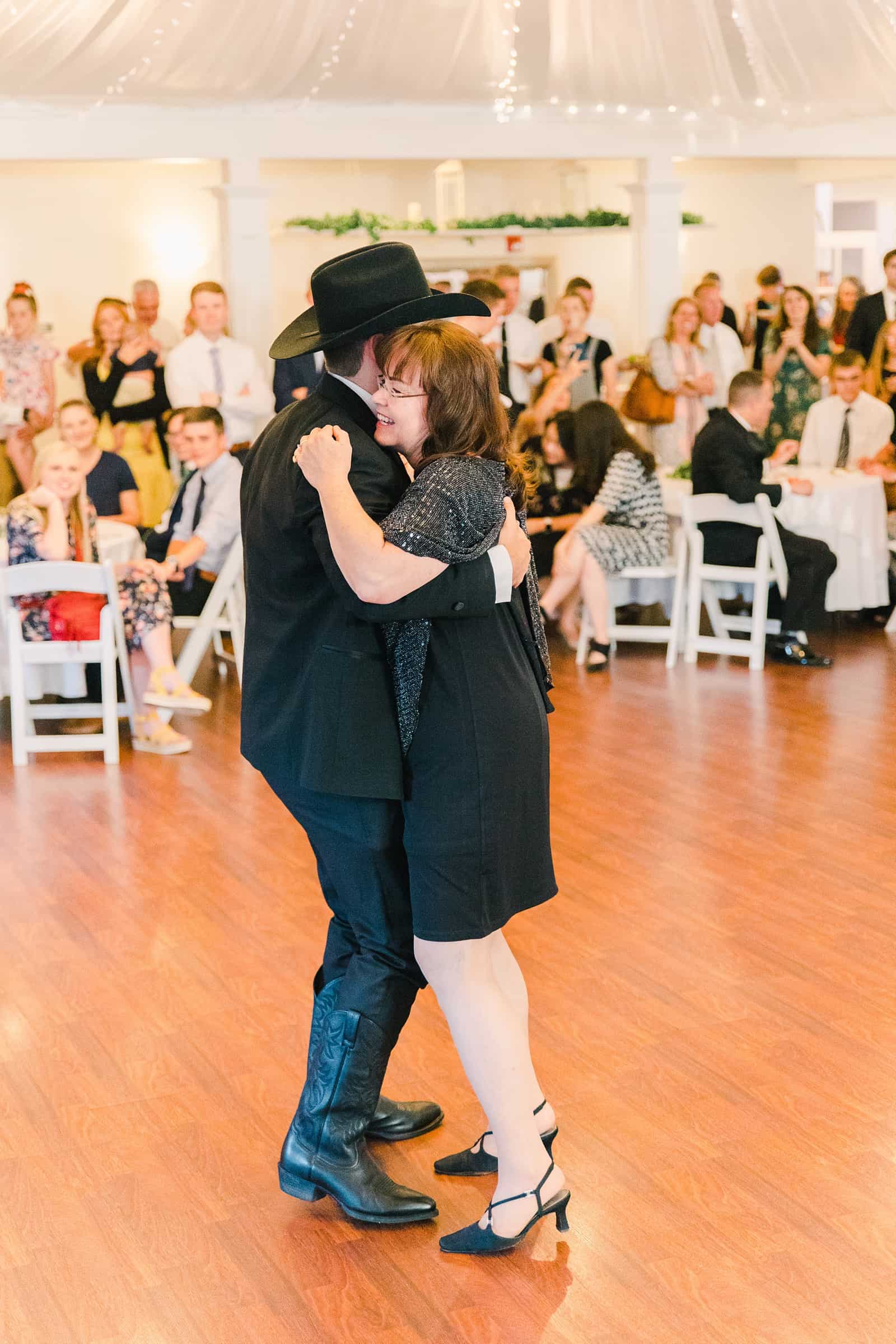 Clarion Gardens Payson Utah Wedding, groom wears cowboy hat and dances with mother of the groom