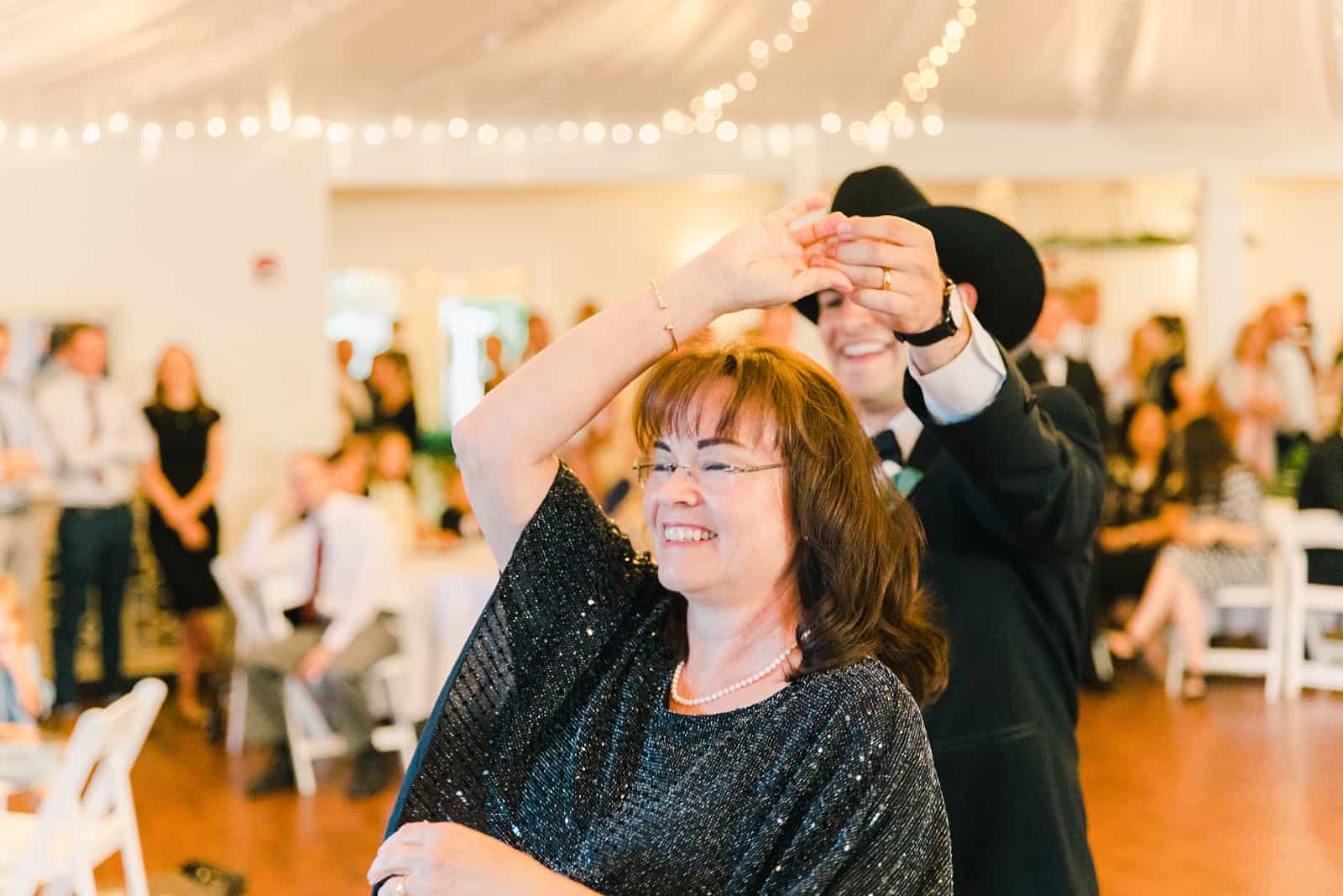 Clarion Gardens Payson Utah Wedding, groom wears cowboy hat and dances with mother of the groom