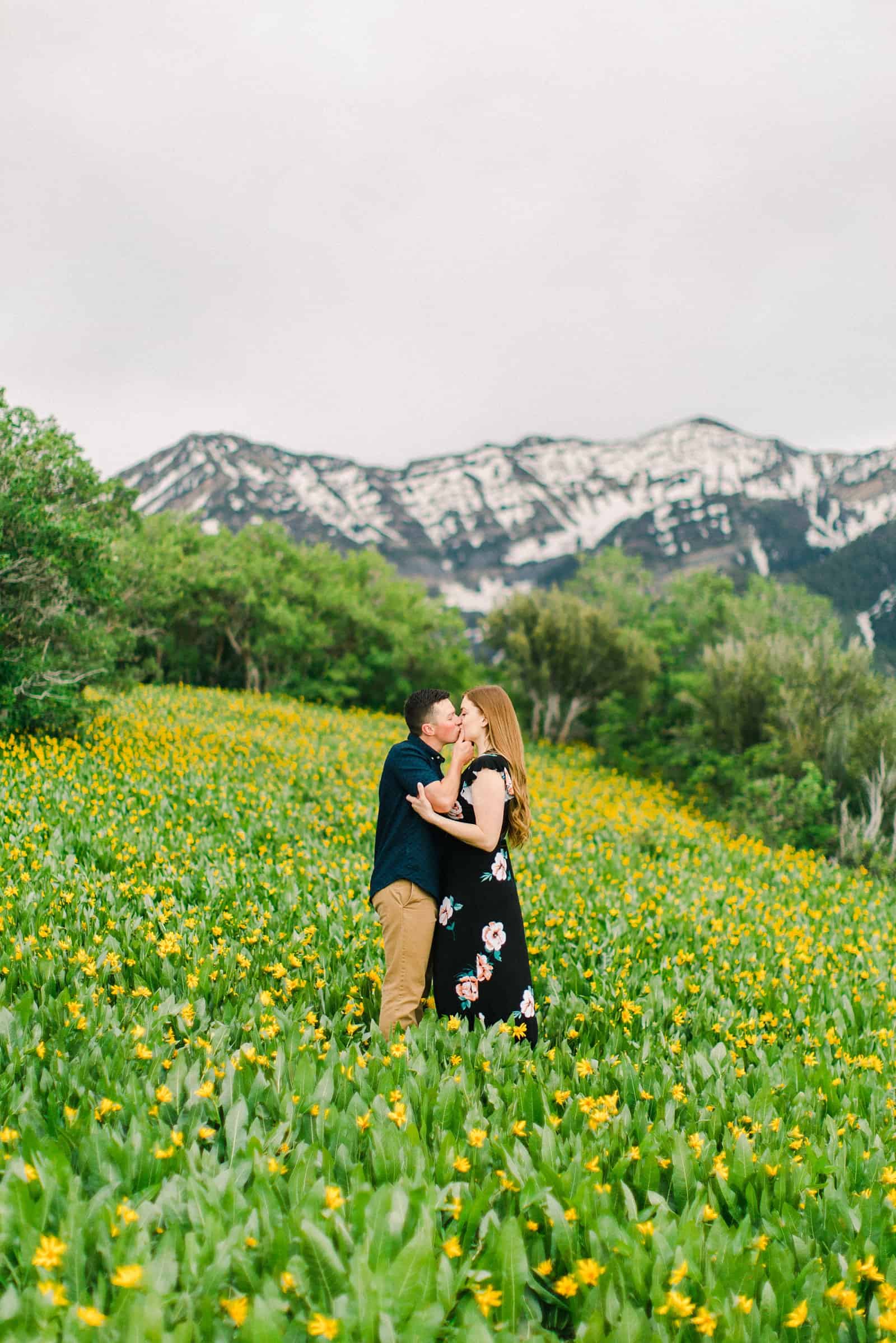 Provo Canyon wildflowers field engagement session, Utah wedding photography, engaged couple kissing in yellow flowers and mountains