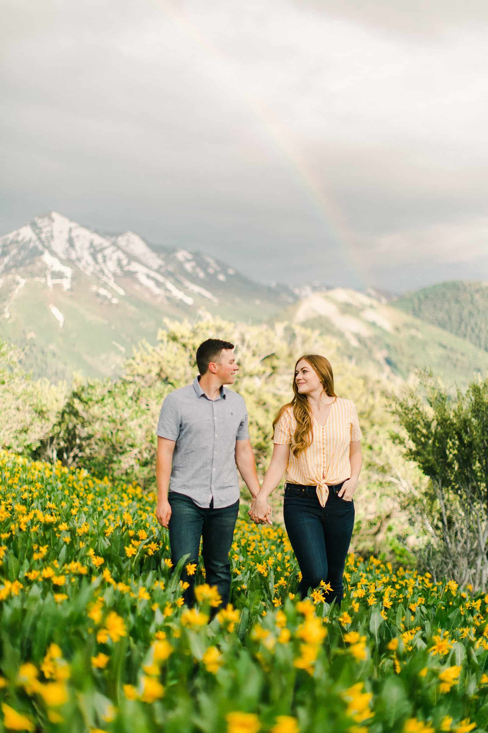 Provo Canyon wildflowers field engagement session, Utah wedding photography, engaged couple walking in yellow flowers and mountains with rainbow in background