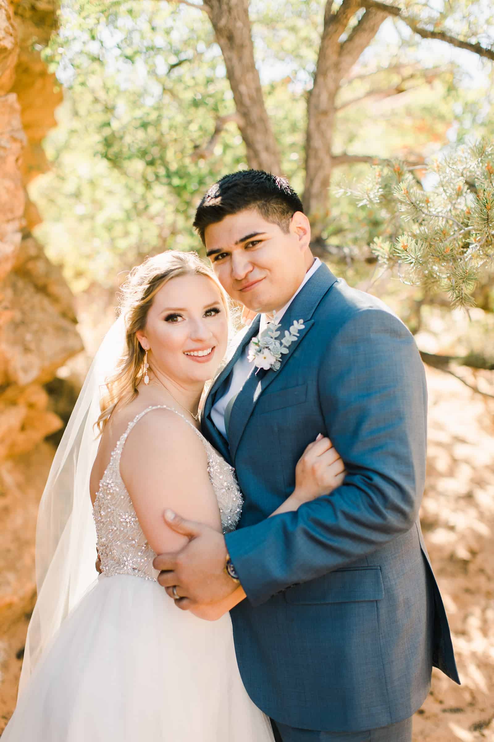 bride and groom smile among red rocks