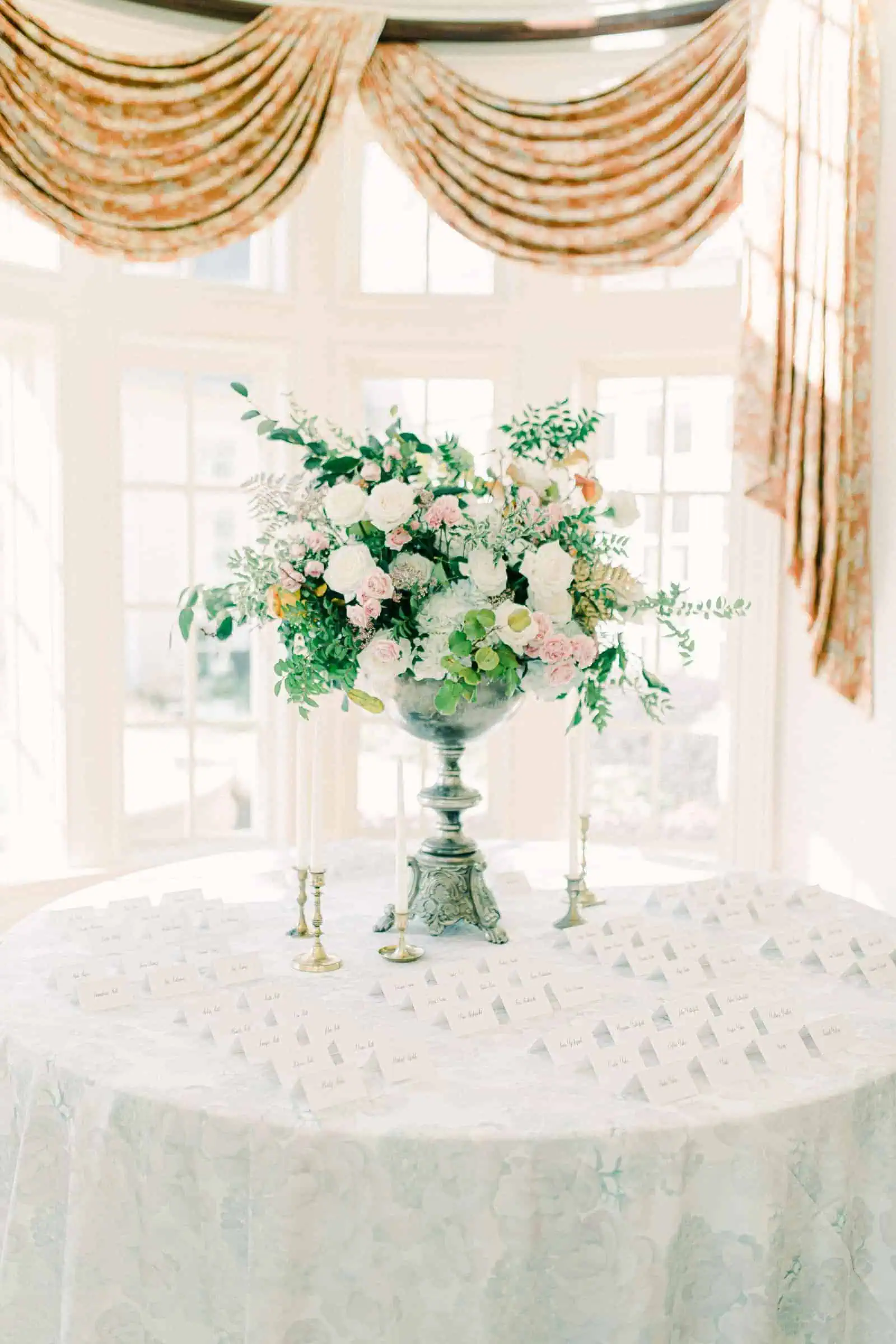 Tall wedding centerpiece with pink and white flowers, calligraphy place cards on light blue tablecloth