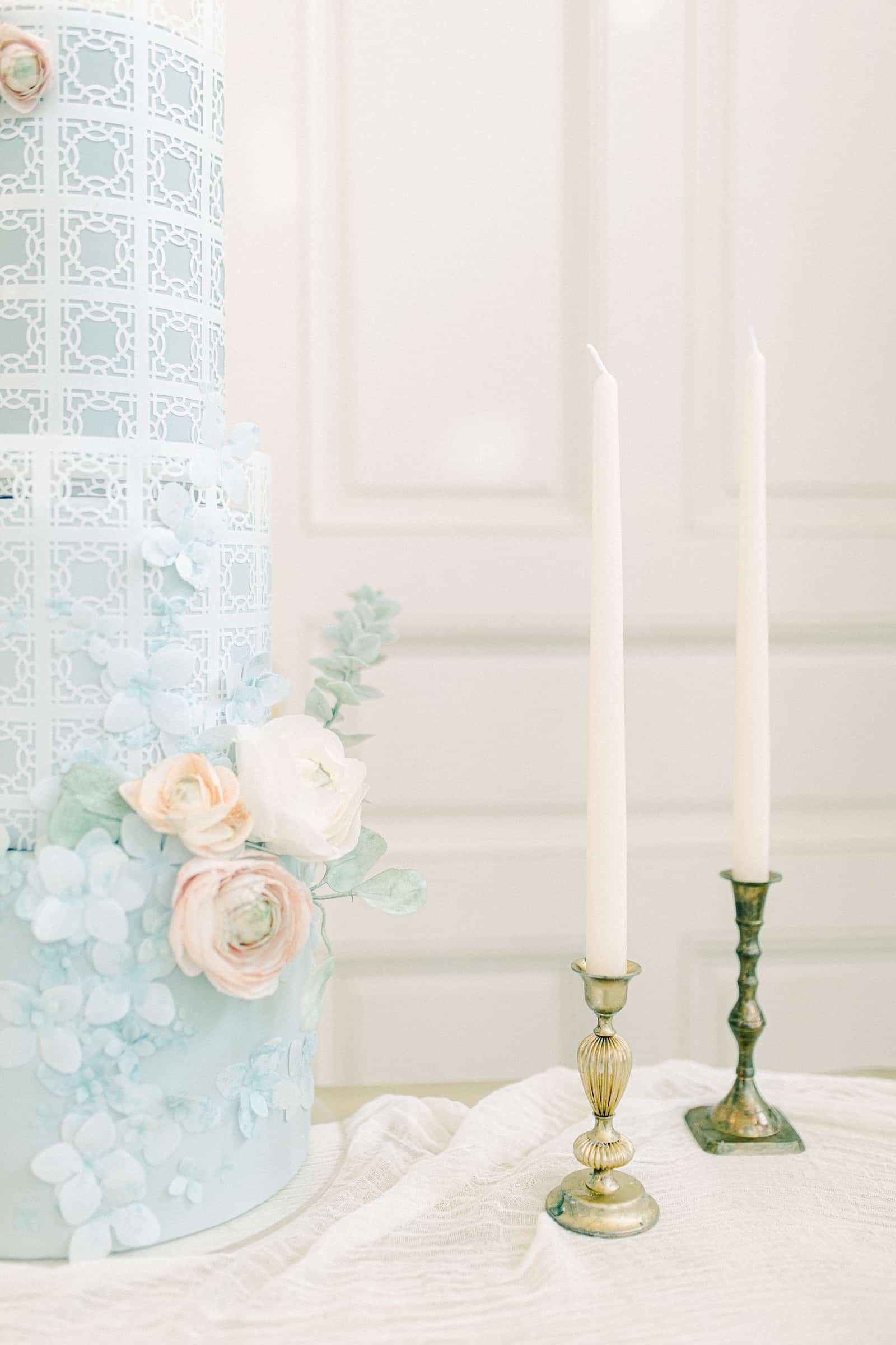 Light blue wedding cake with pink and white sugar flowers with gold candlesticks