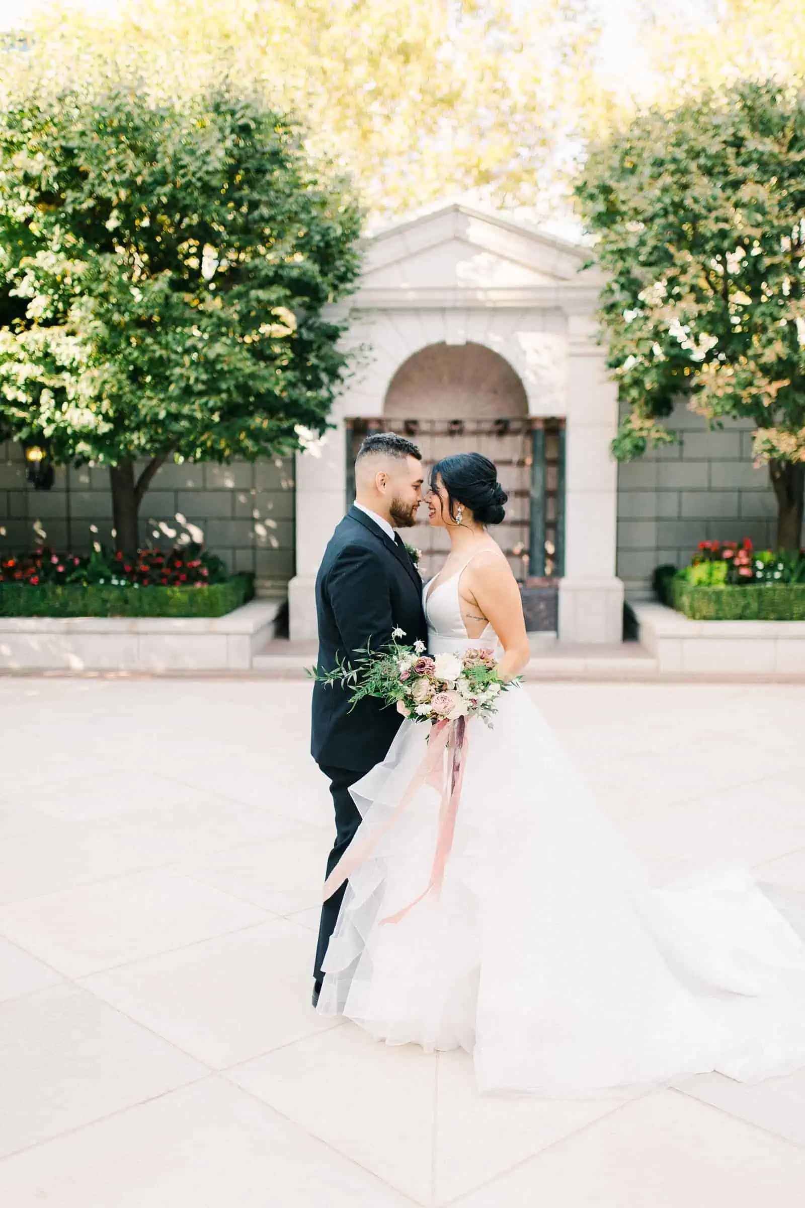 Bride and groom pose with foreheads together outside the Grand America Hotel