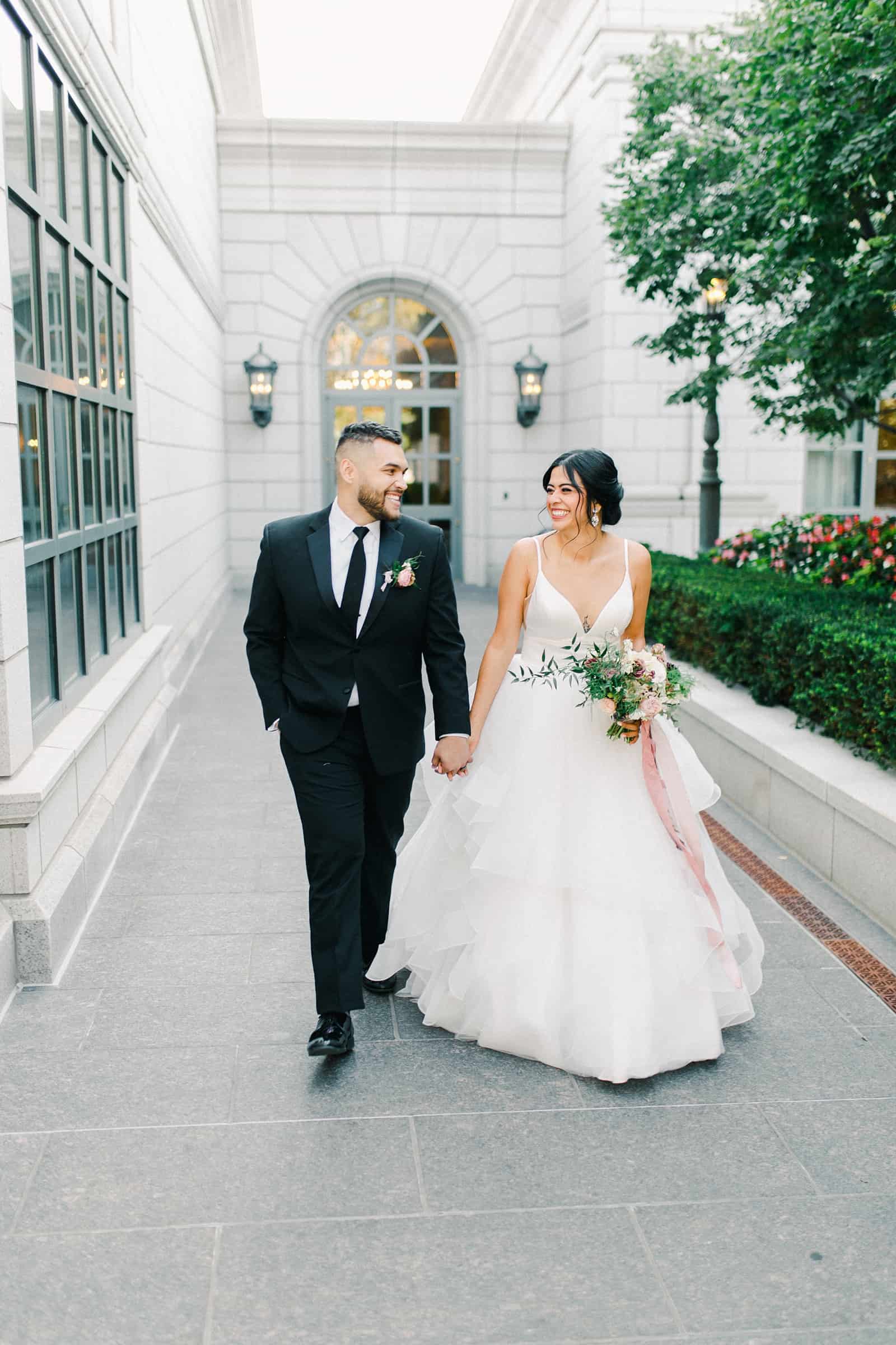 Bride and groom walking together inside the Grand America hotel courtyard