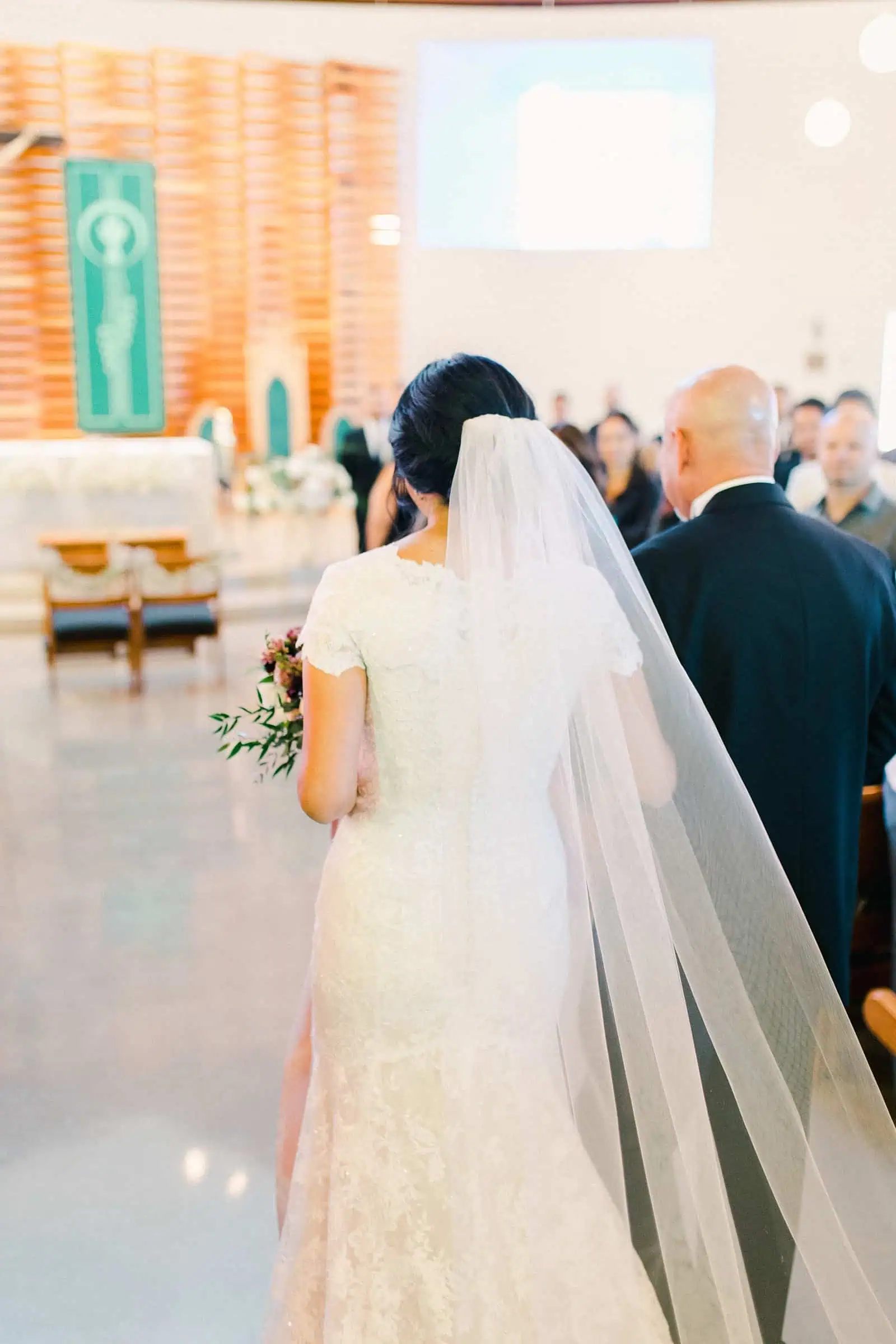 father of the bride walks her down the aisle with long veil and train