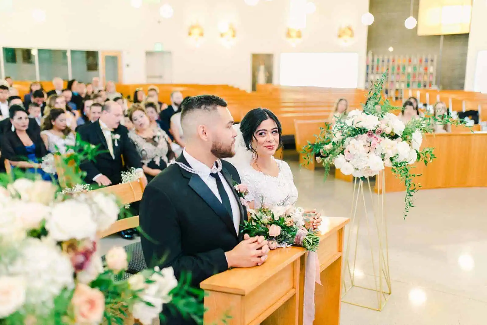 Bride and groom kneel during traditional catholic mass ceremony