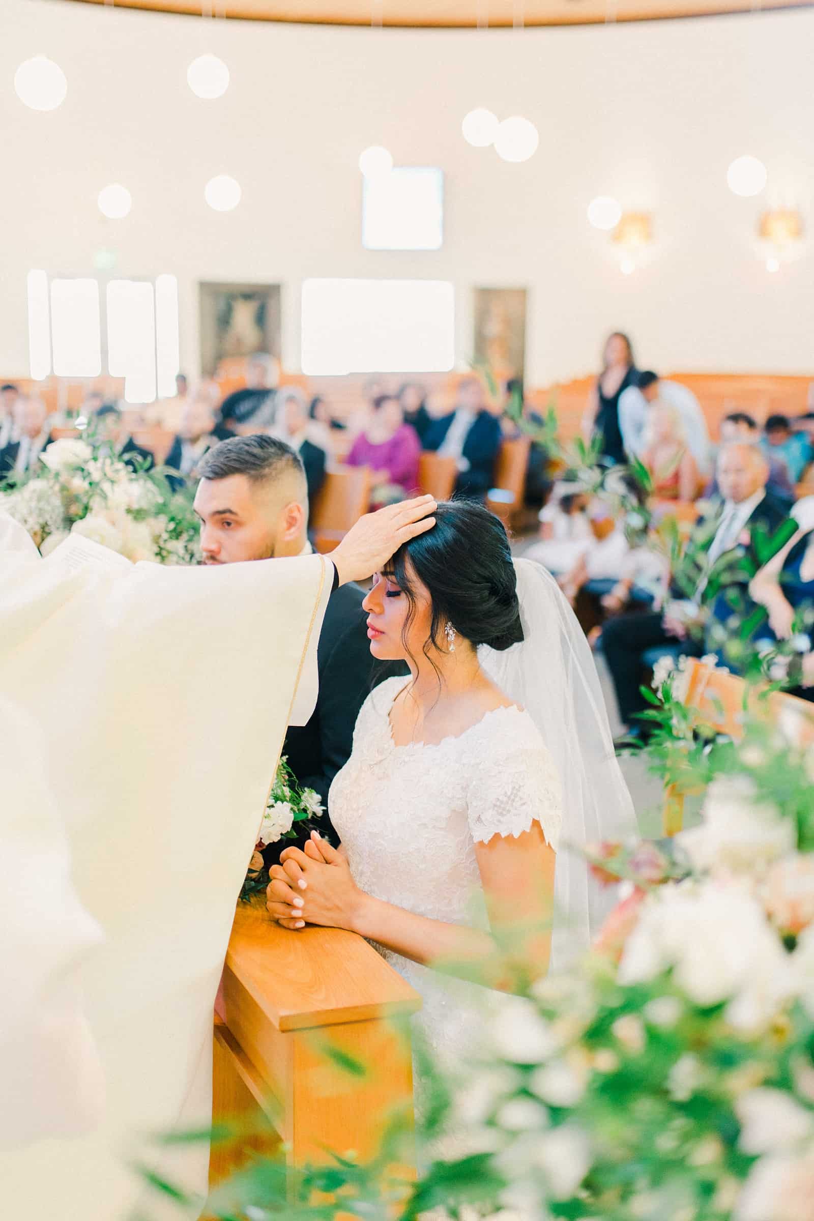 Bride with priest pray during catholic wedding ceremony