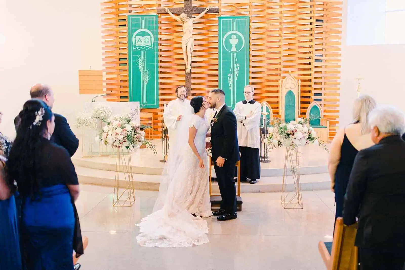 Bride and groom kiss during traditional Catholic ceremony