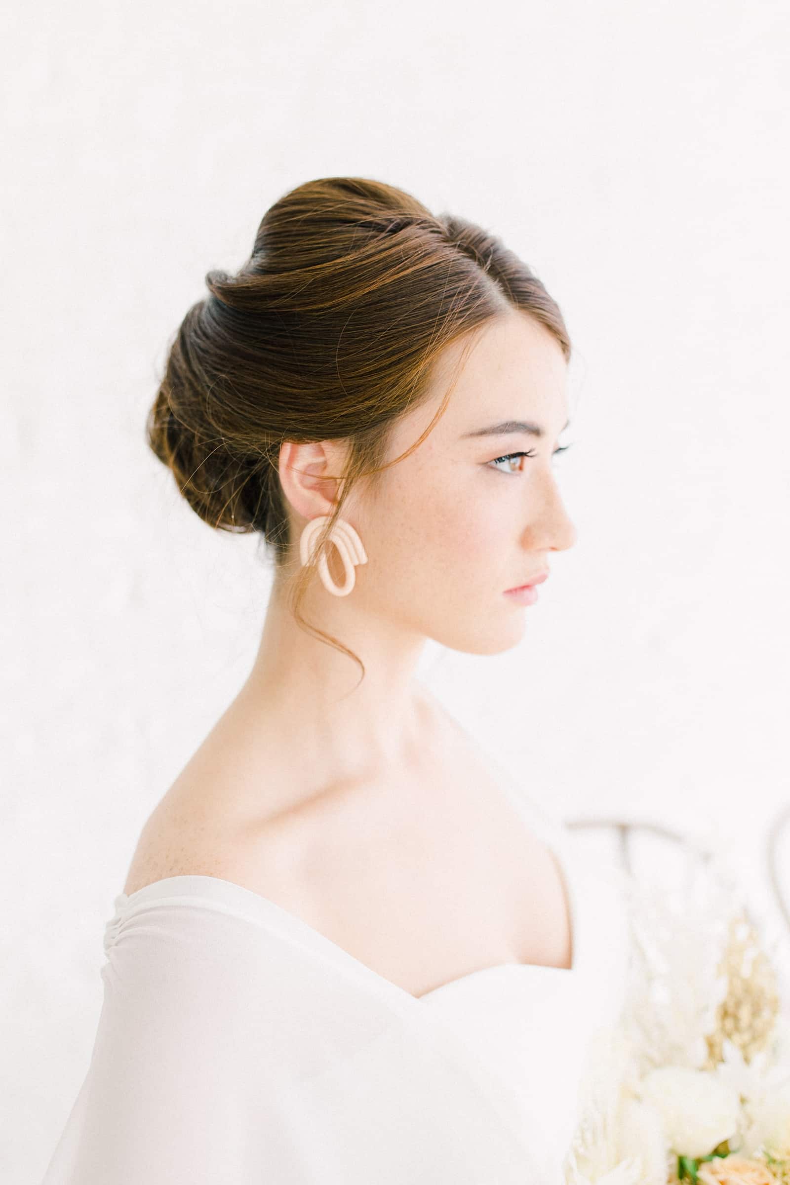 Modern bride with sleep updo, statement earrings and sweetheart neckline