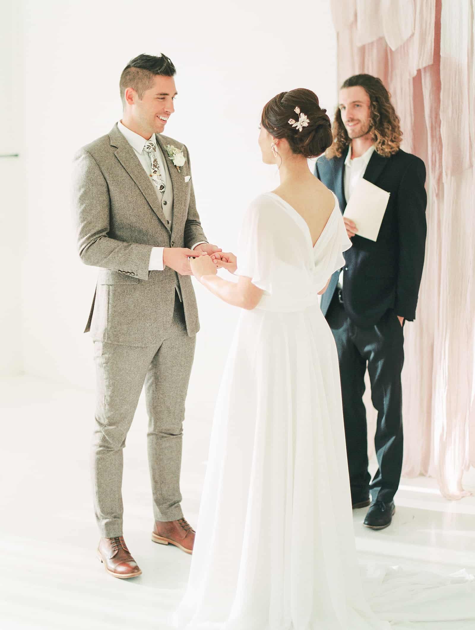 Groom in beige gray suit says his vows and smiles