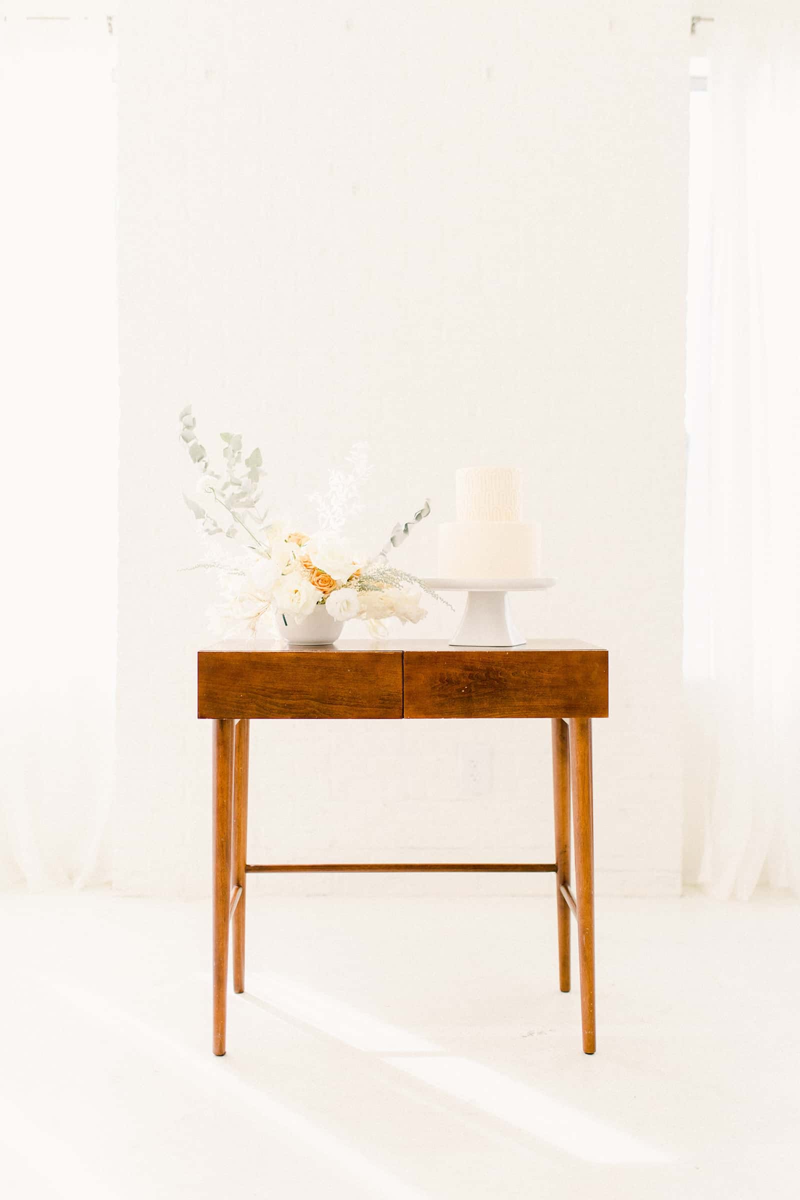 Modern wooden wedding cake table with minimalist neutral flowers