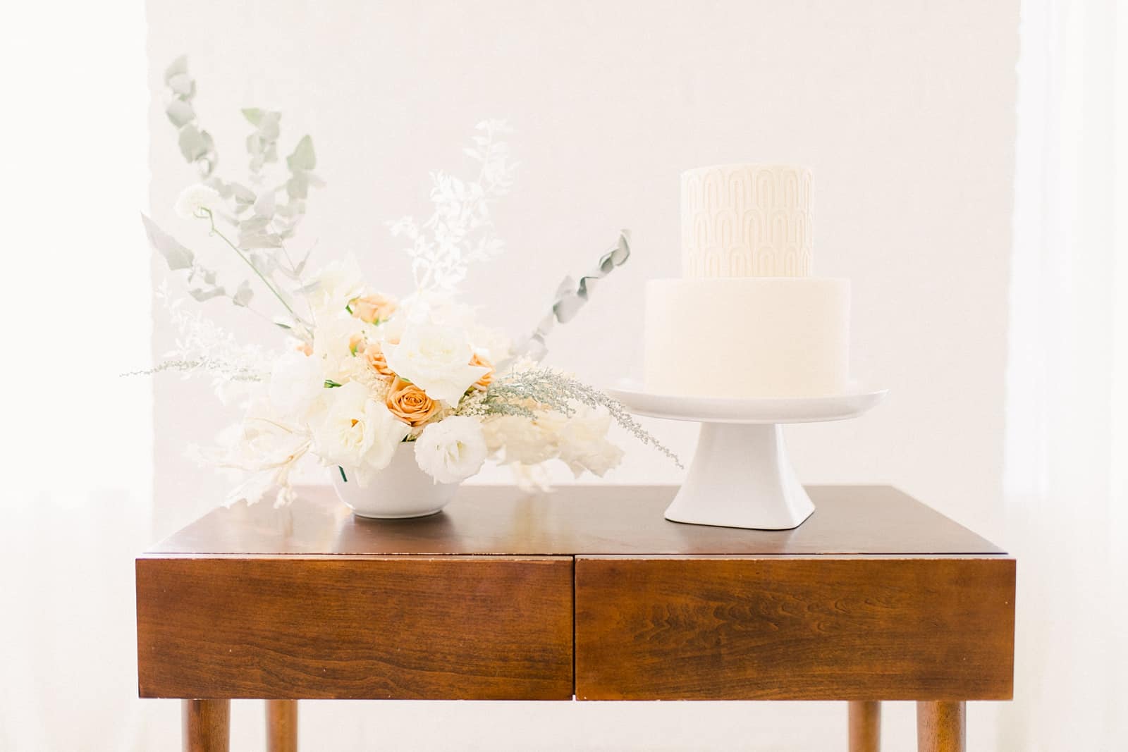 Modern wooden wedding cake table with minimalist neutral flowers