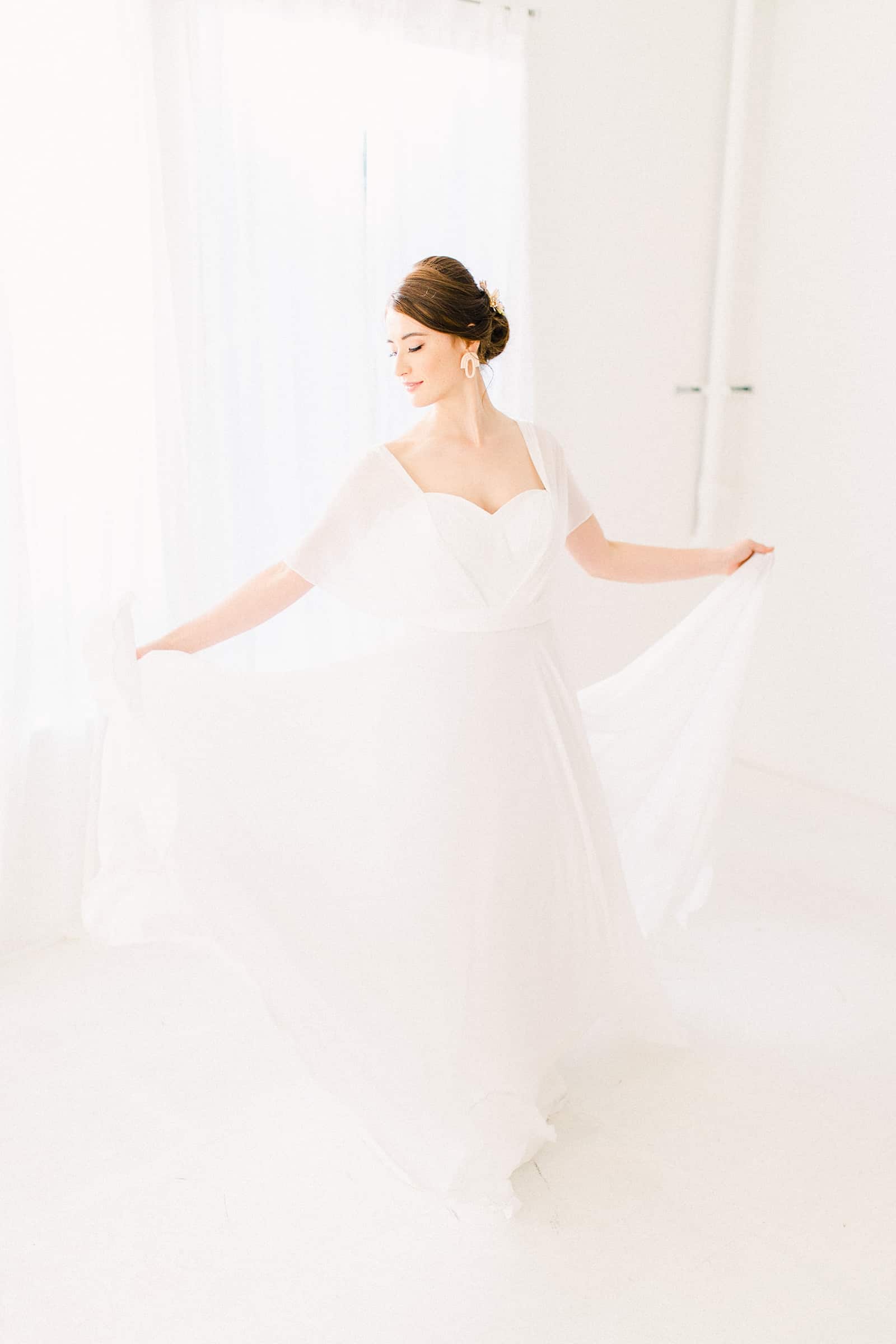 Bride wearing simple modern chiffon flowy wedding dress with sweetheart neckline