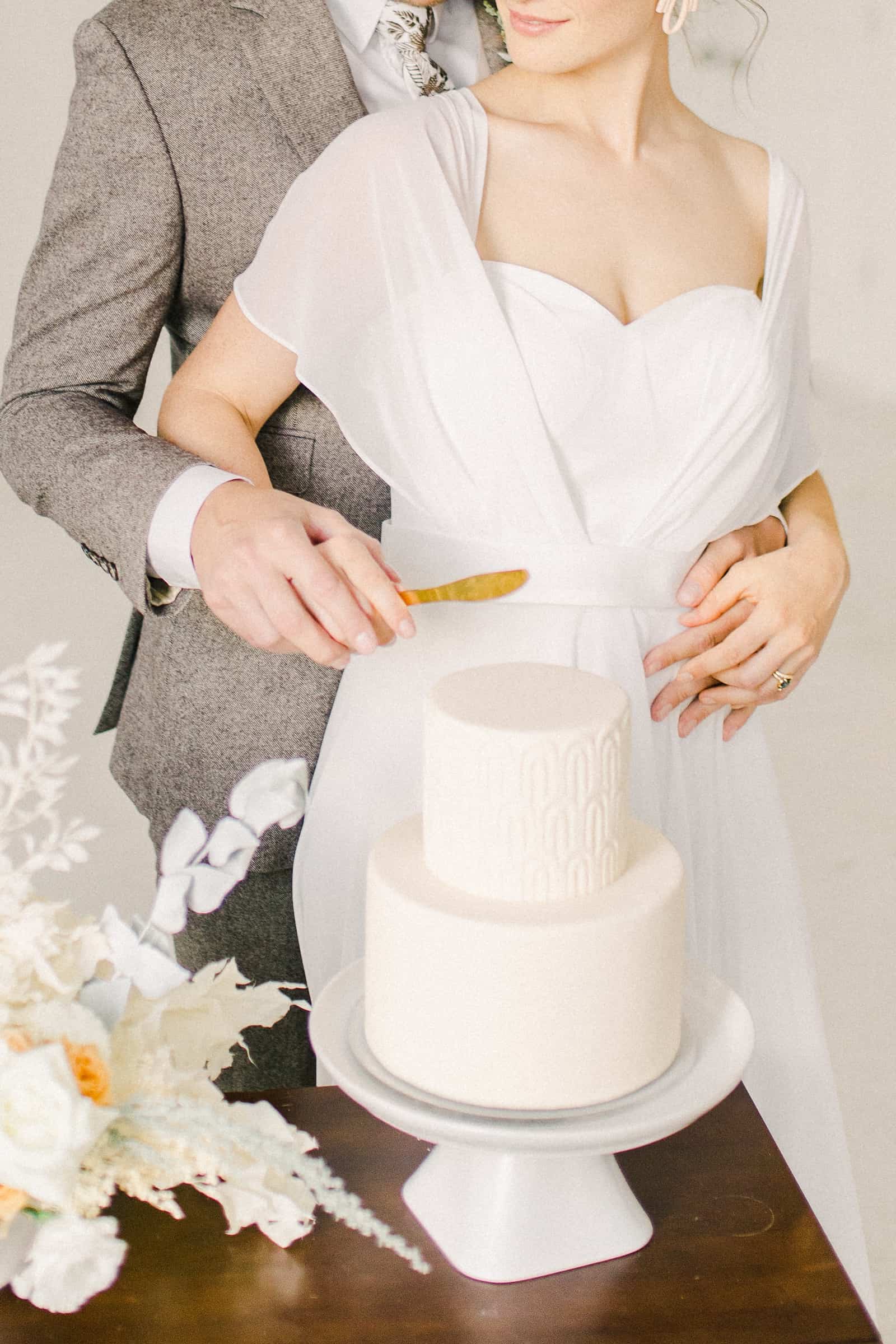 Bride and groom cut the cake, Modern minimalist white wedding cake with geometric design