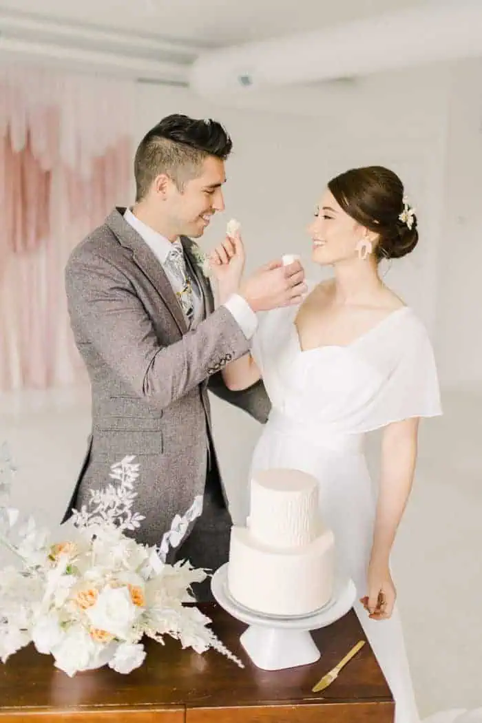 Bride and groom feed each other wedding cake, modern wedding