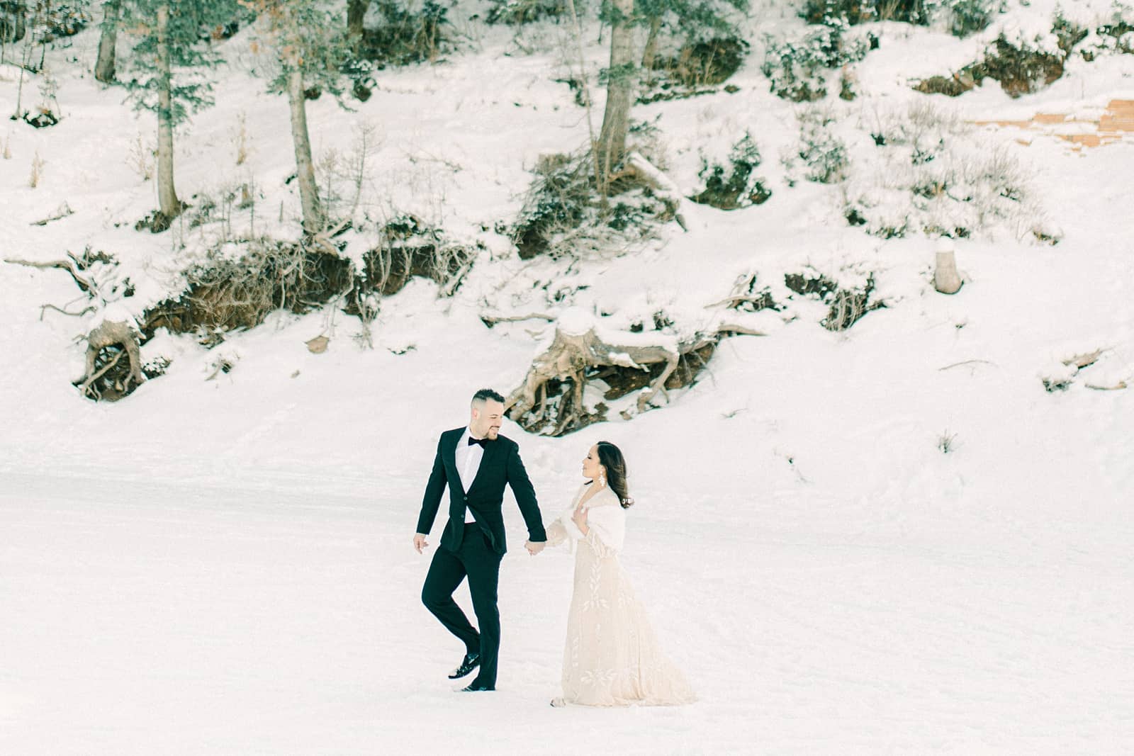 Bride and groom walking in the snow at Tibble Fork Reservoir in American Fork Canyon, Utah