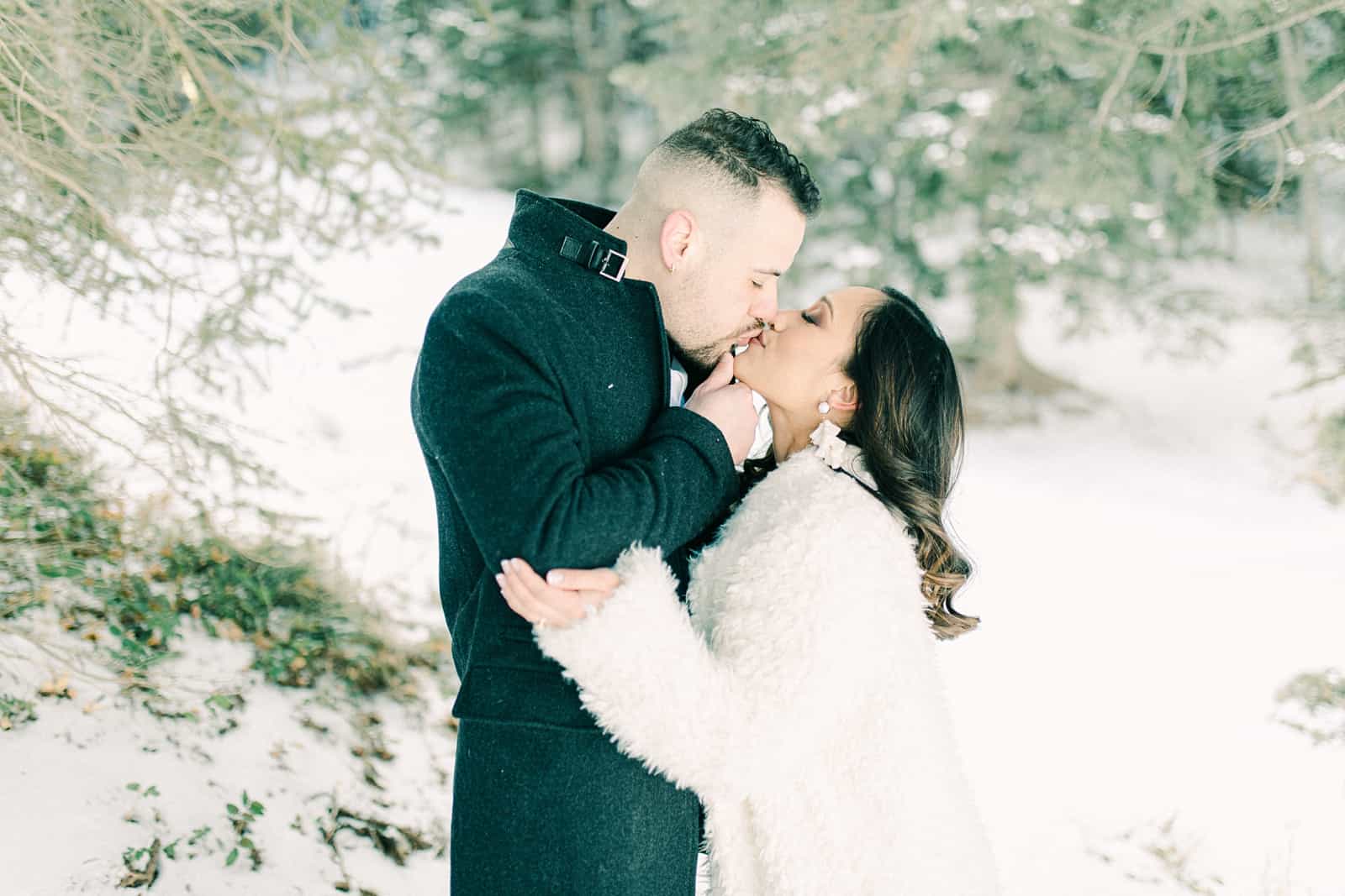 Bride and groom kiss in the winter woods