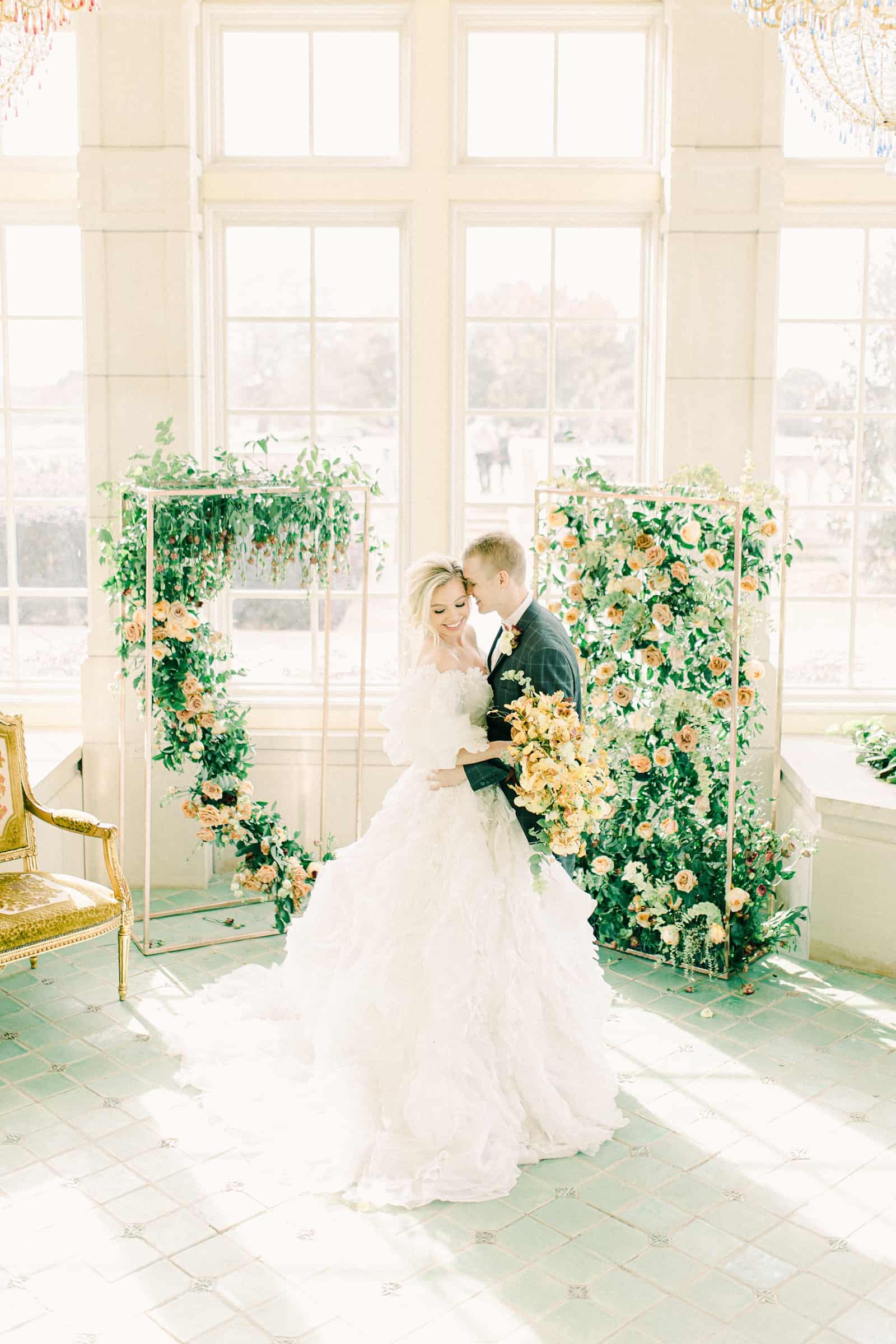 Bride and groom during wedding ceremony surrounded by flower backdrop, destination wedding photography