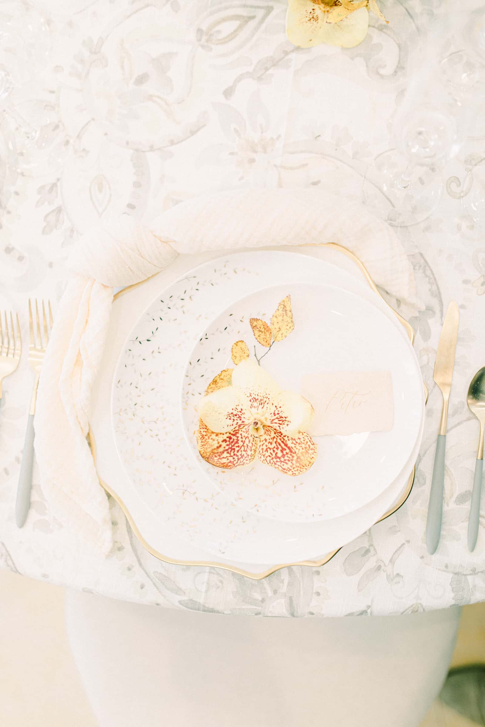 Fine art wedding table place setting with gray watercolor table cloth and orange orchid