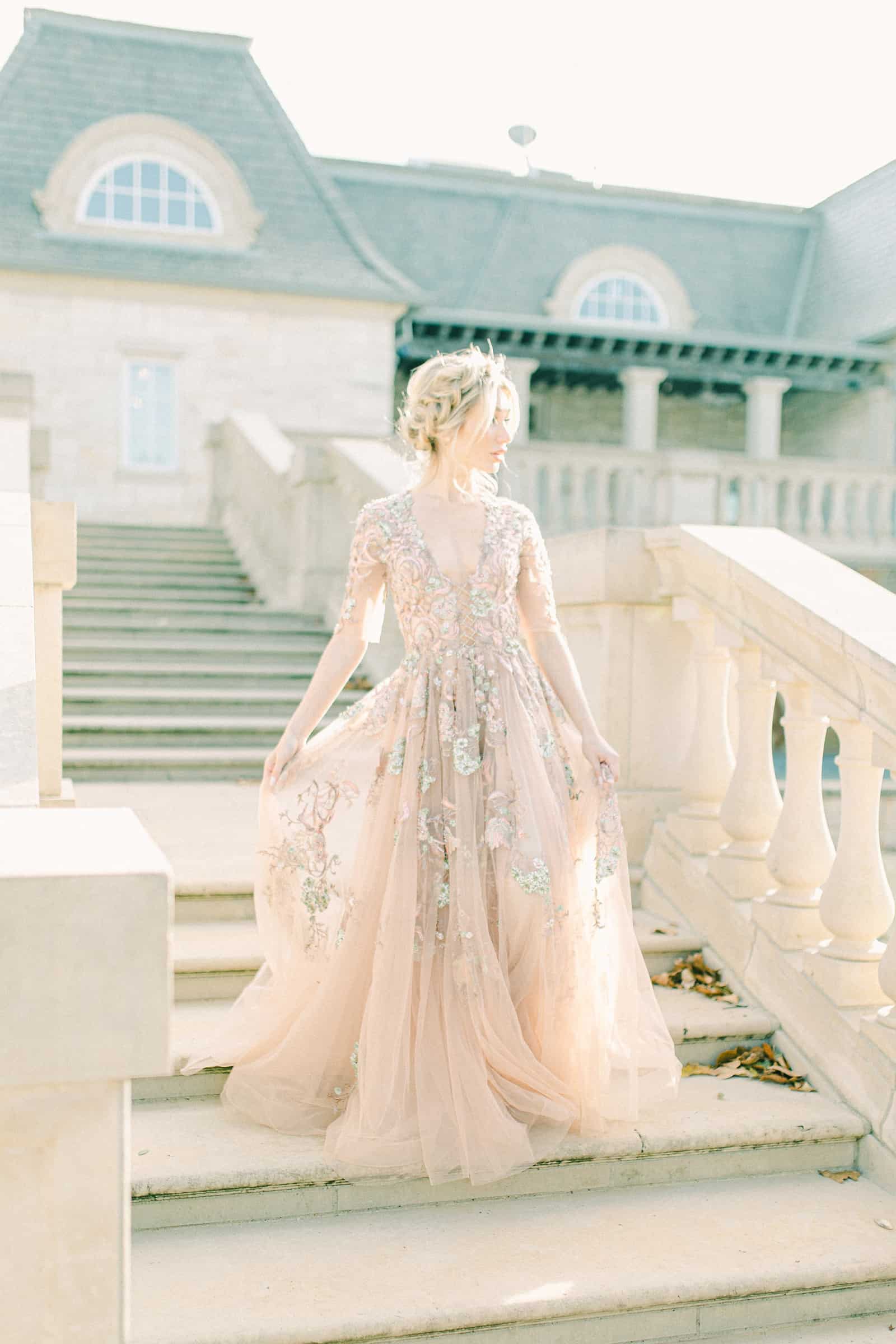 Bride walking down staircase wearing YSA Makino couture wedding dress with floral embellishments and embroidery, flowy wedding dress